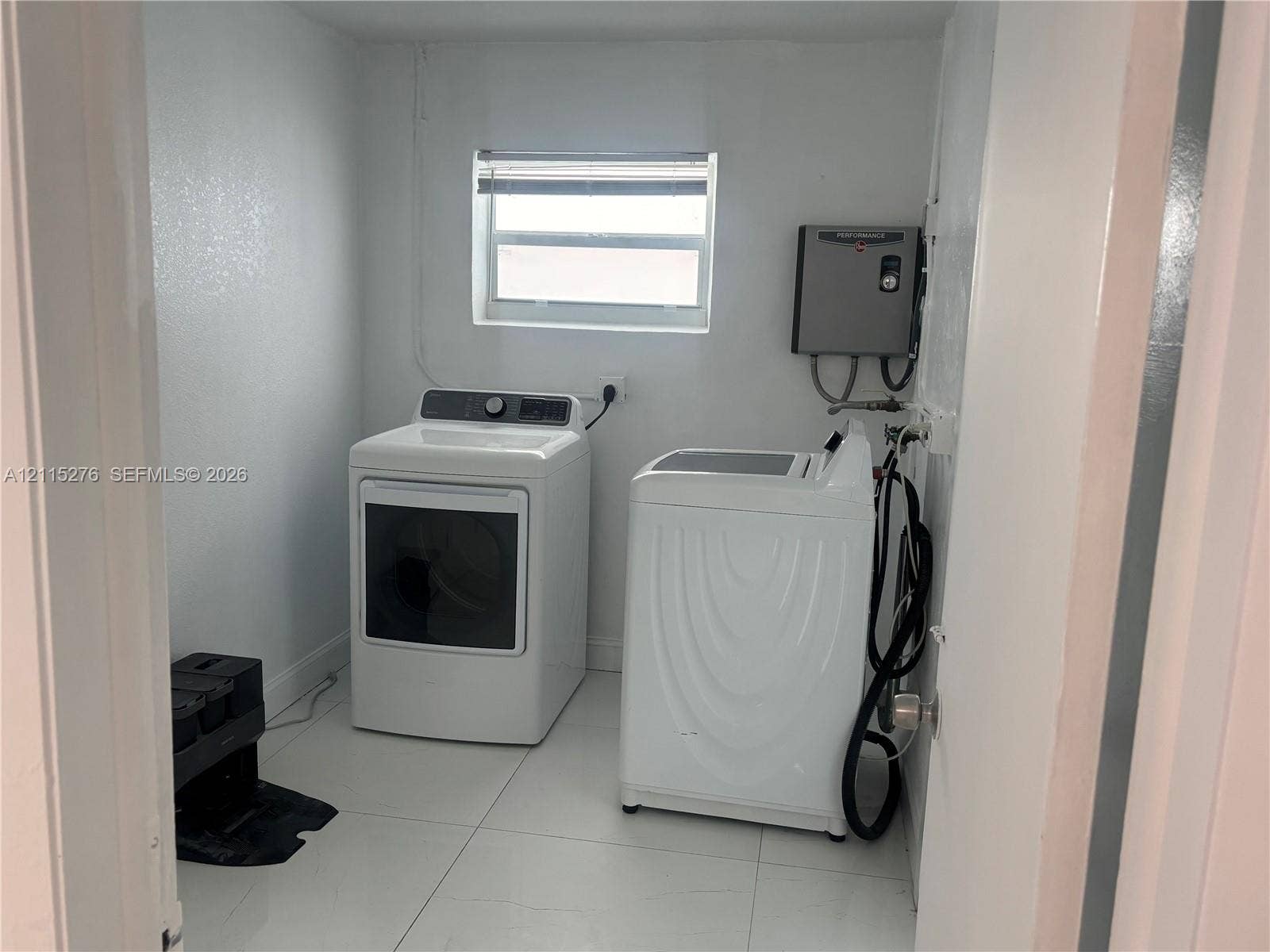 Davie, FL 33314 Laundry area featuring neutral-toned tile flooring, white walls, and a window with blinds
