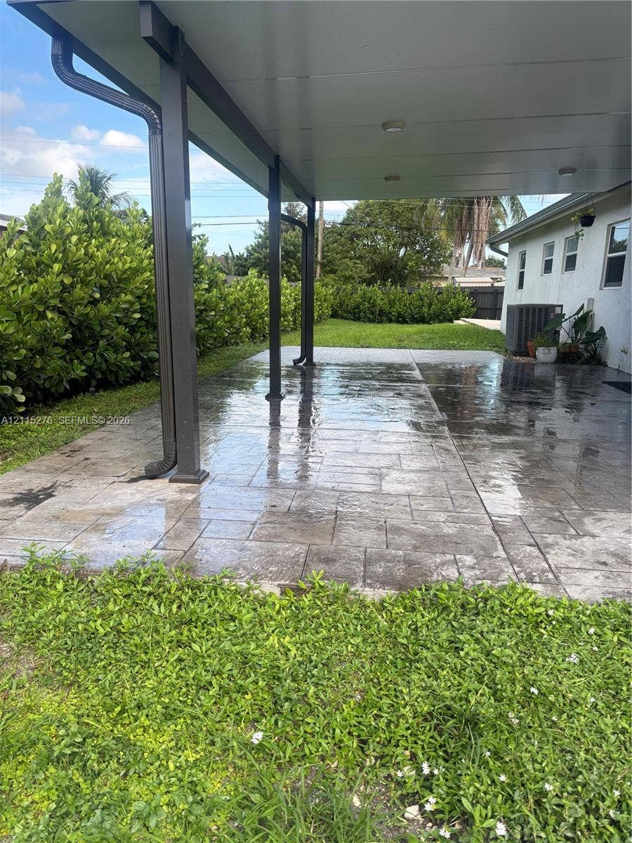 Davie, FL 33314 Covered patio featuring stamped concrete flooring, a solid roof structure, and perimeter shrubbery