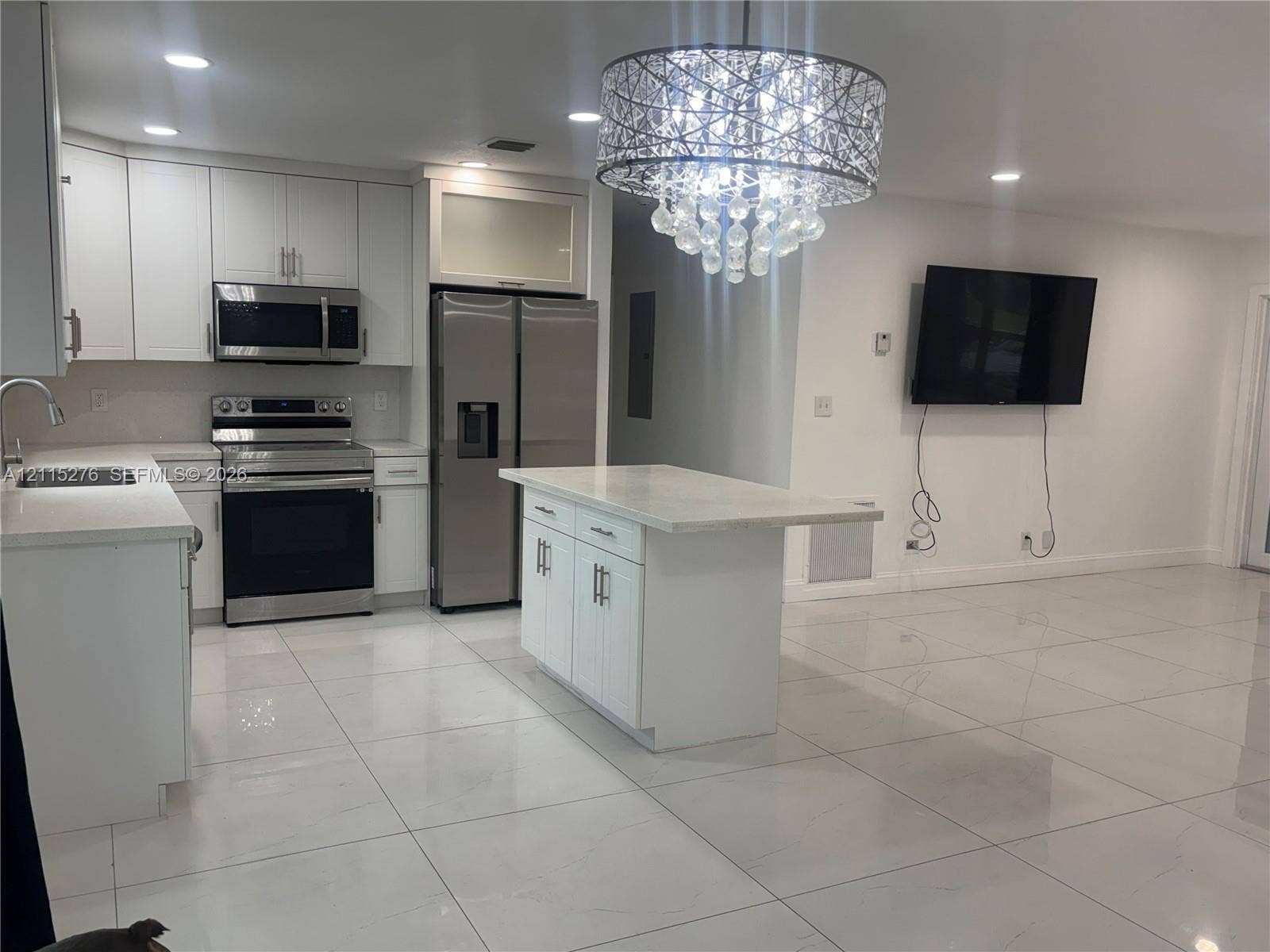 Davie, FL 33314 Kitchen featuring white shaker-style cabinetry, quartz countertops, stainless steel appliances, a central island, and large-format tile flooring