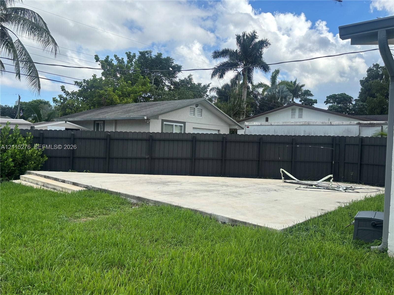 Davie, FL 33314 Backyard featuring a raised concrete patio and a dark-toned privacy fence