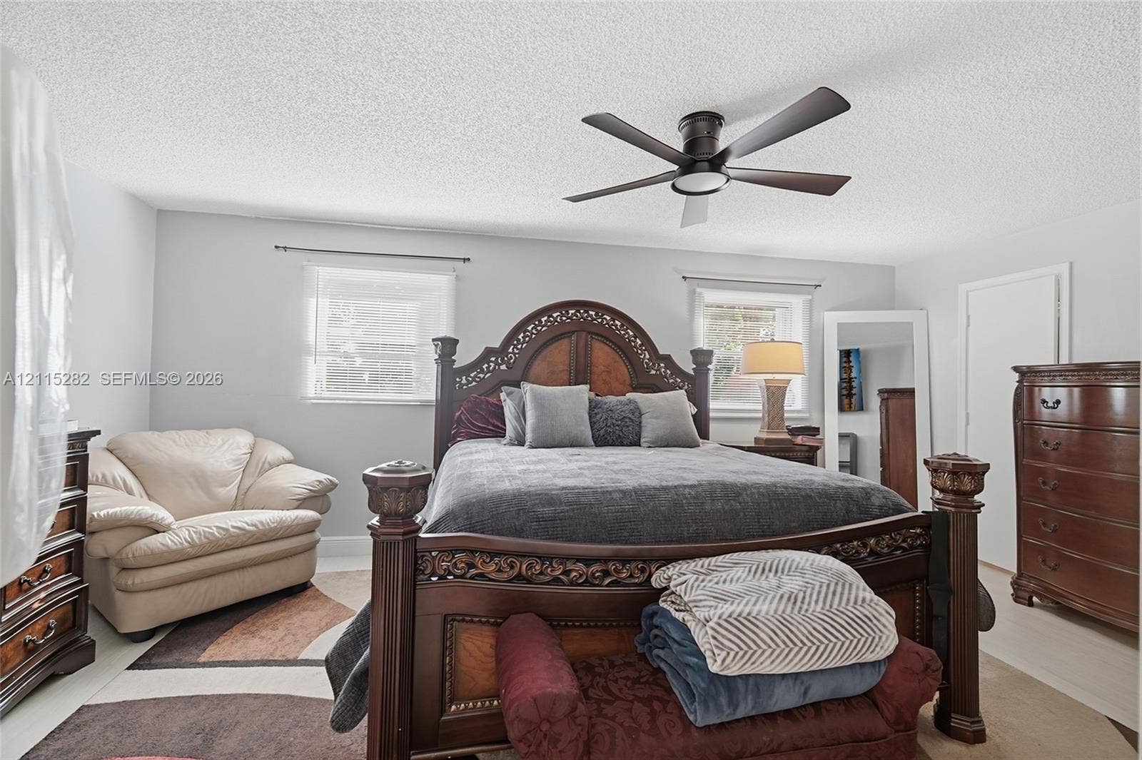 Neutral-toned room featuring a central ceiling fan with an integrated light fixture and dual windows with metal rods