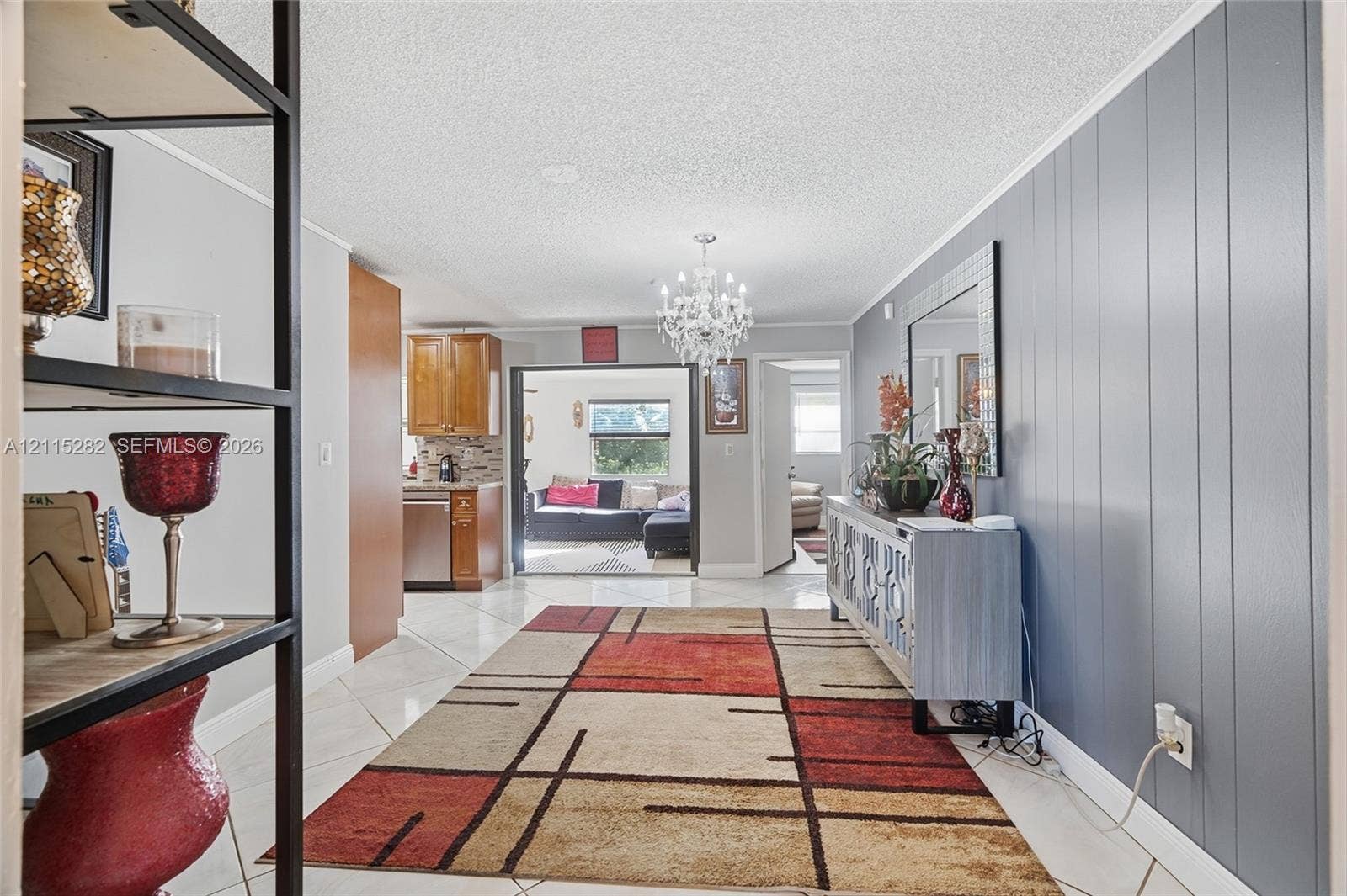Interior featuring ceramic tile flooring, a multi-tiered crystal chandelier, and a vertical wood-paneled accent wall