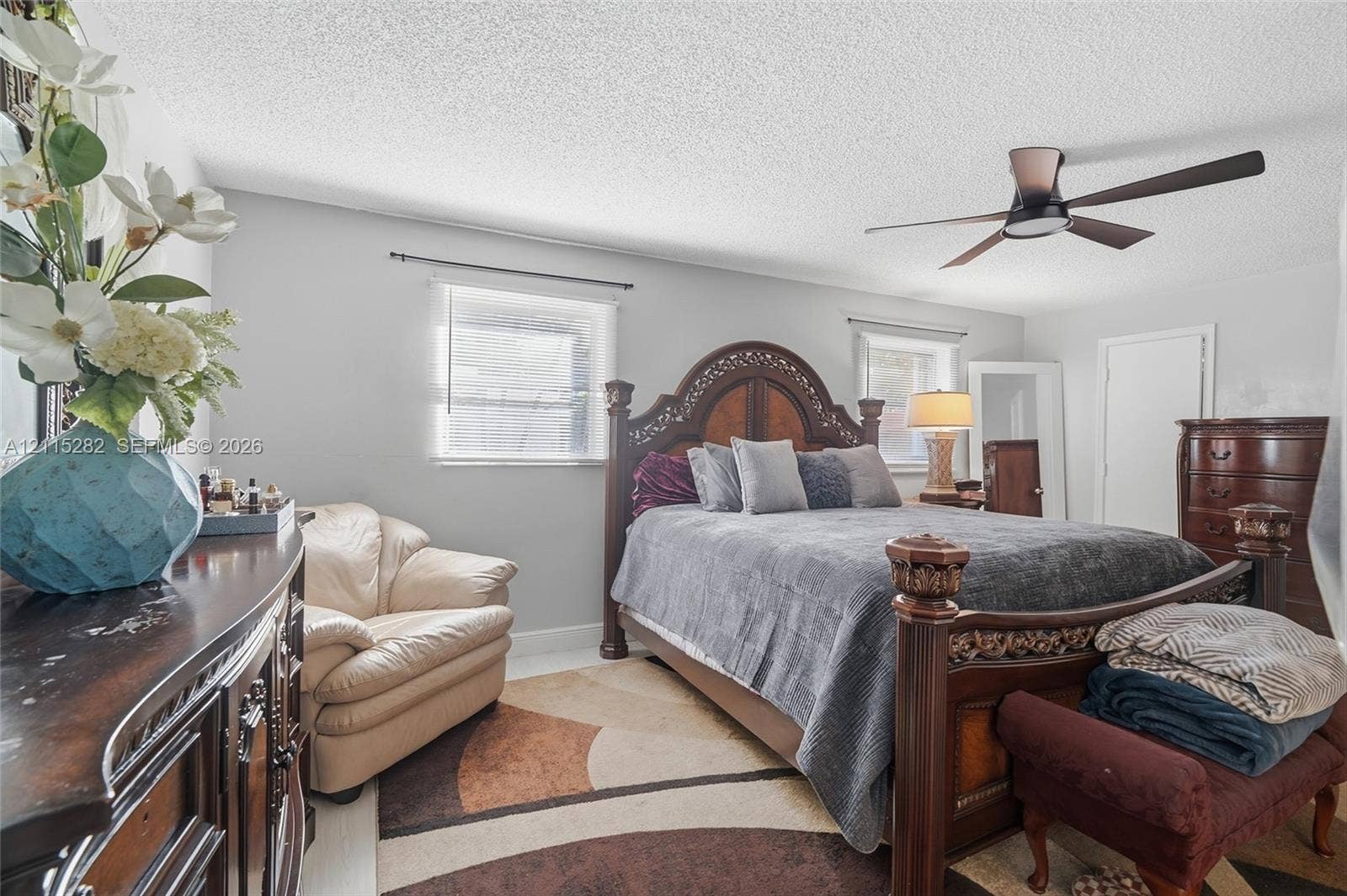 Bedroom featuring a multi-blade ceiling fan, dual windows with curtain rods, and solid-surface flooring