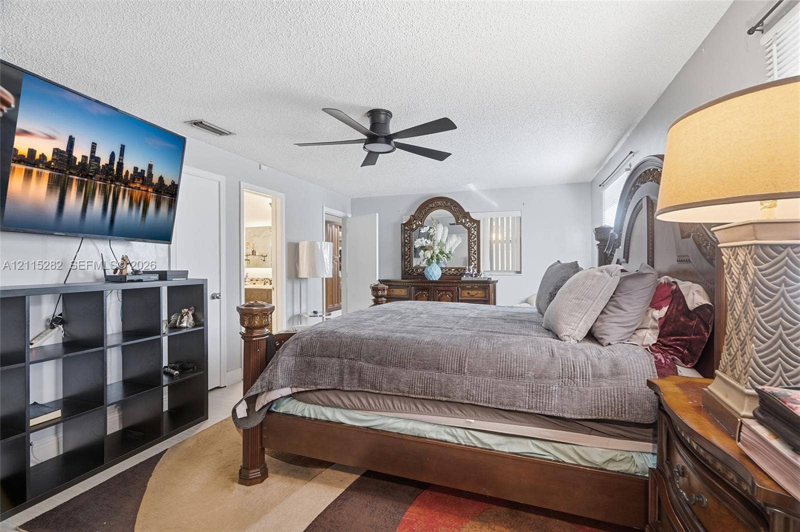 Room featuring a textured ceiling, matte black ceiling fan, and window blinds