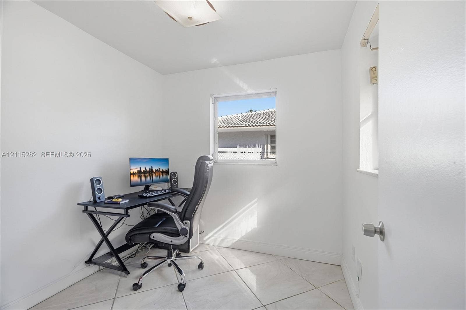 Neutral-toned interior space featuring polished tile flooring, white walls, flush-mount ceiling lighting, and a square window