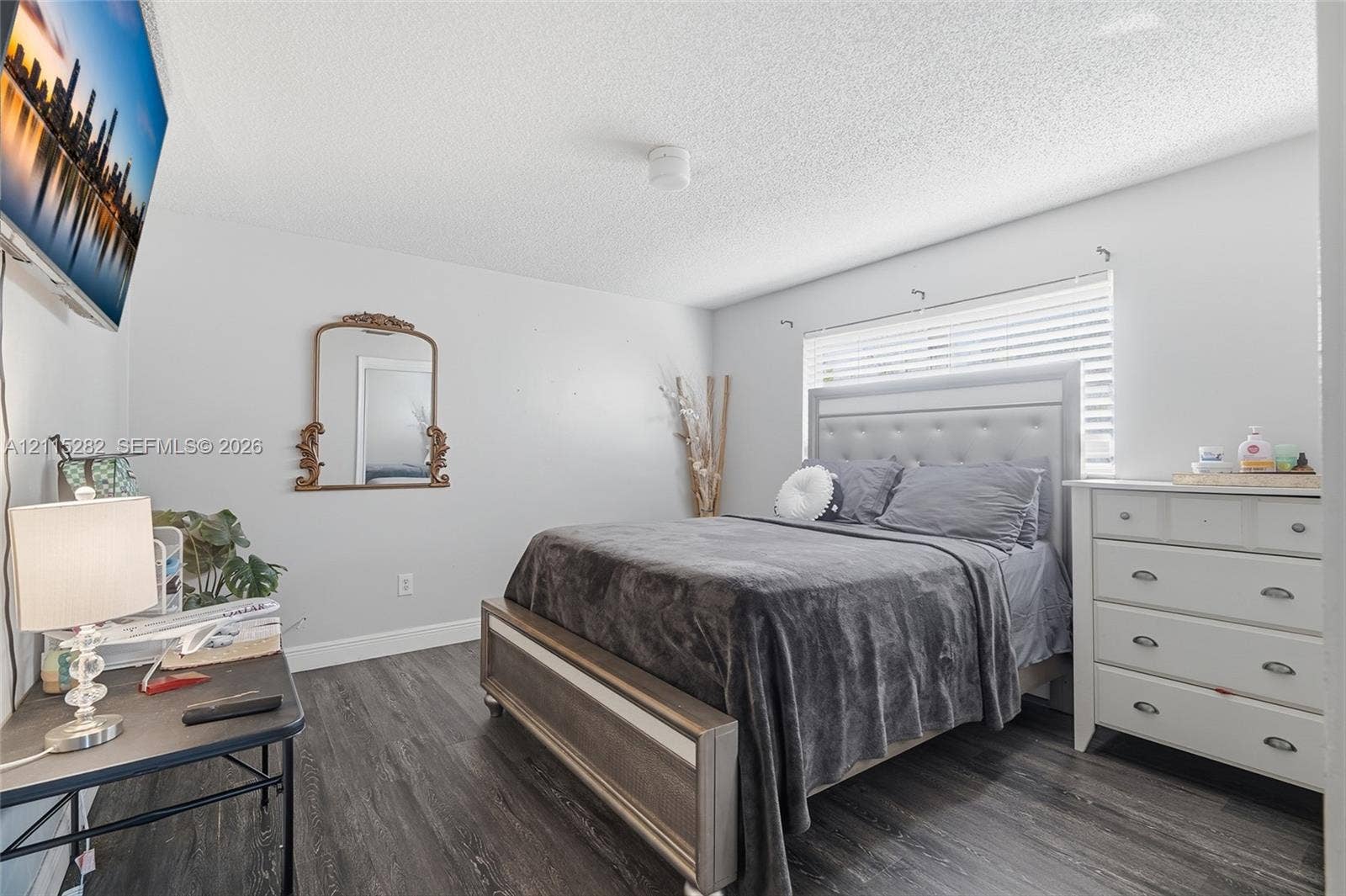 Room featuring wood-finish flooring, a neutral color palette, and a window with horizontal blinds