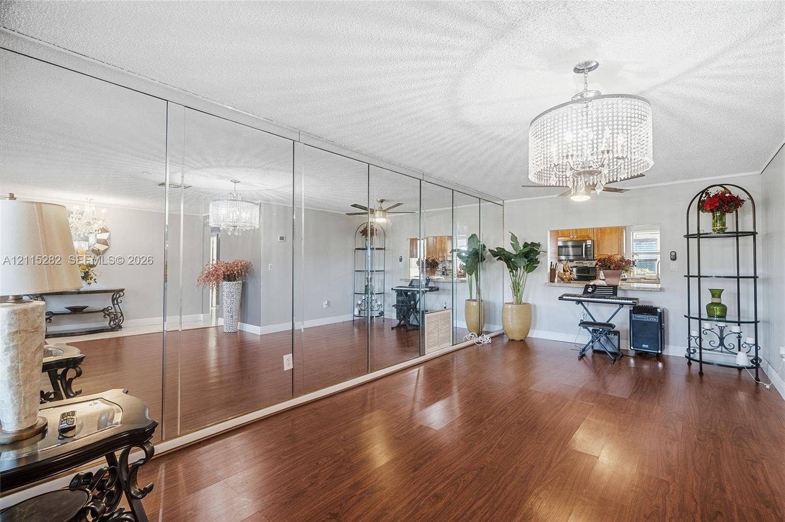 Expansive wall-to-wall mirrored paneling, wood-finish flooring, and a tiered crystal chandelier fixture