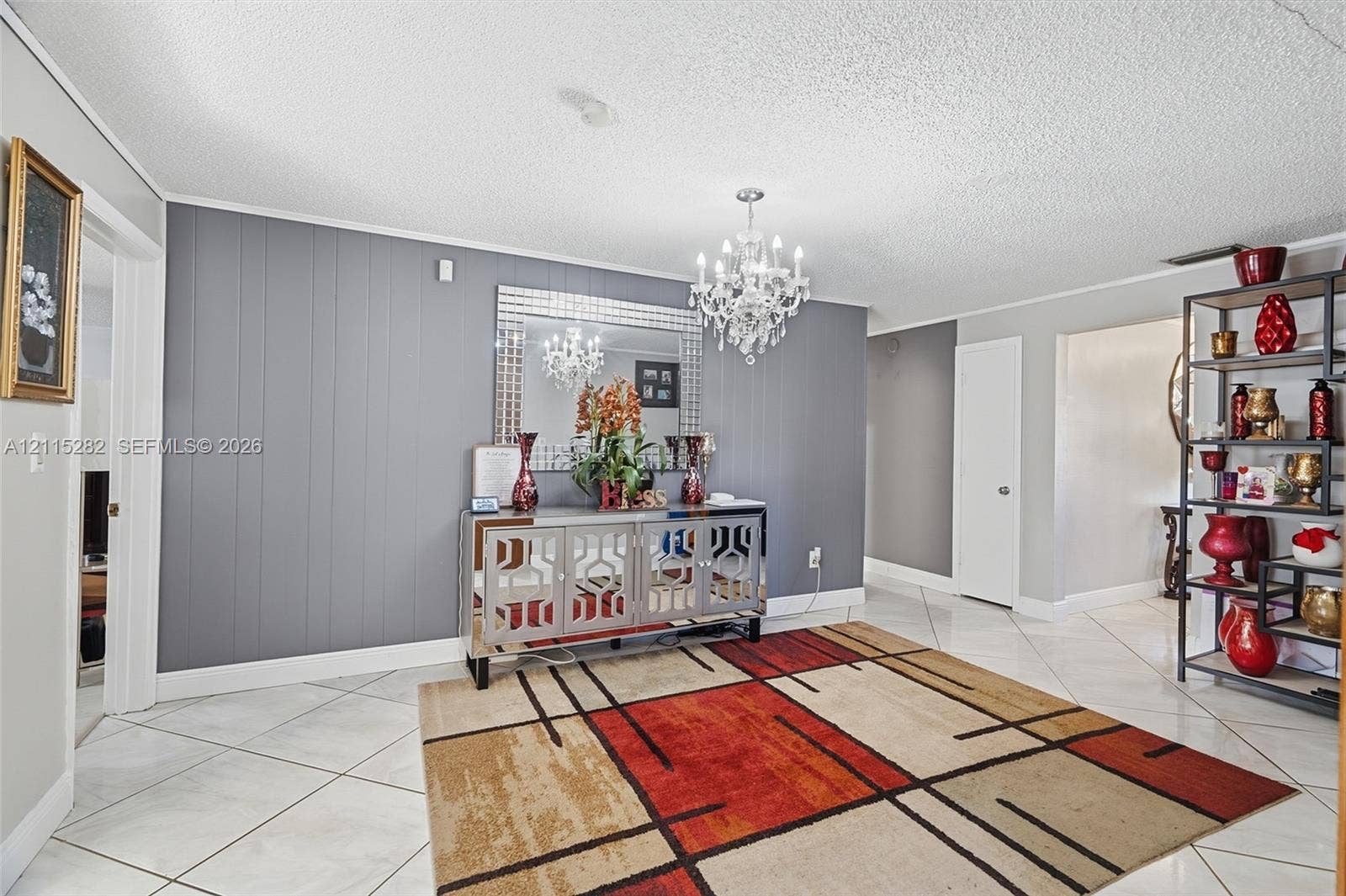 Accent wall with vertical paneling, crystal-style chandelier, and tile flooring