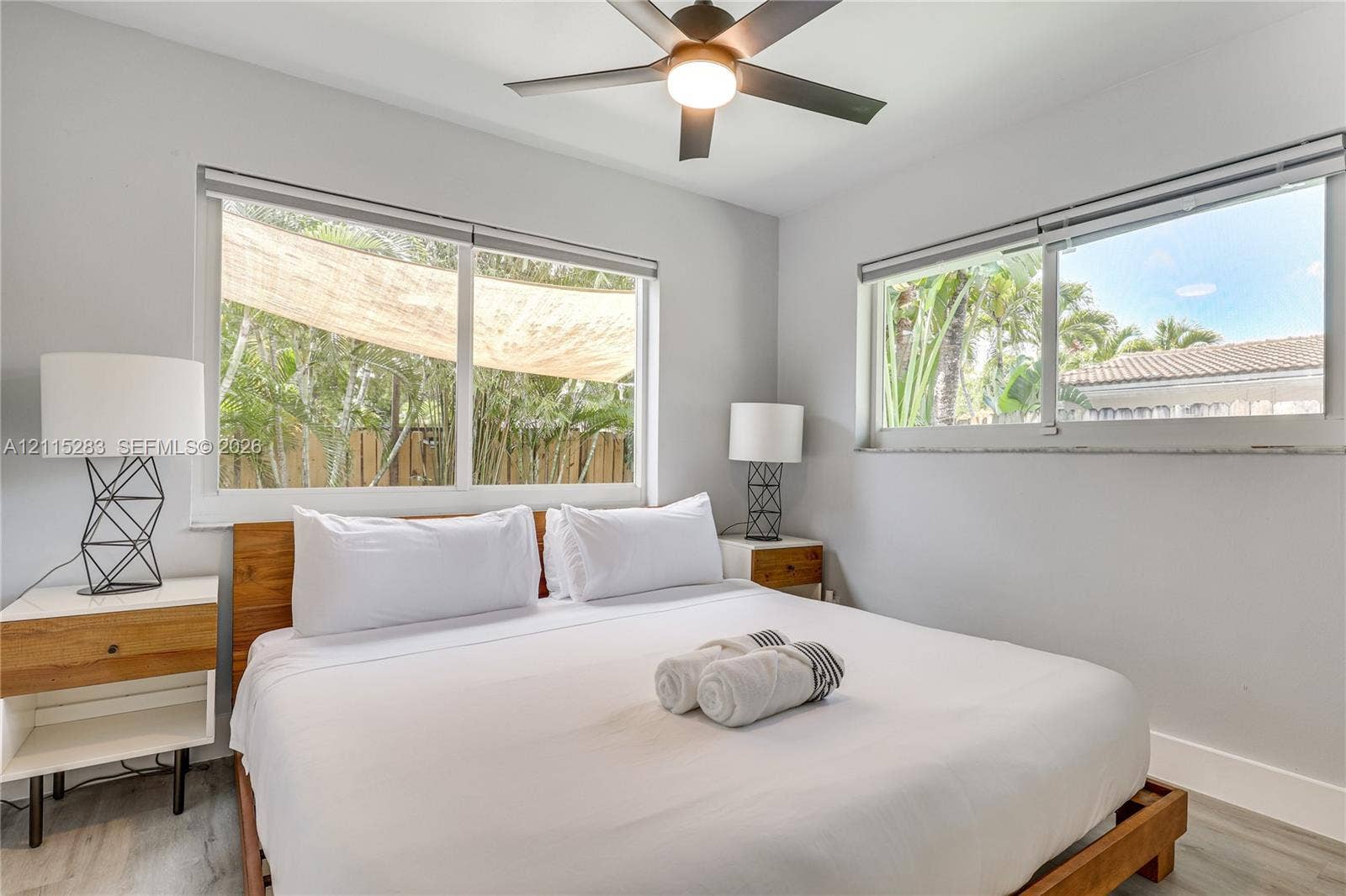 1619a NE 25th Street, #A, Wilton Manors, Wilton Manors, FL 33305 Neutral-toned bedroom featuring large windows, wood-finish flooring, and a ceiling fan with integrated lighting