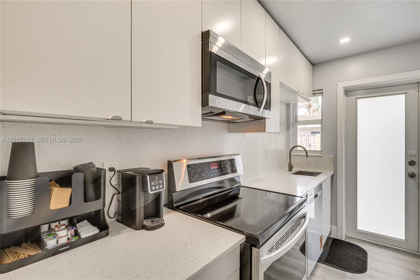 1619a NE 25th Street, #A, Wilton Manors, Wilton Manors, FL 33305 Kitchen featuring flat-panel white cabinetry, solid-surface countertops, stainless steel appliances, and a modern gooseneck faucet