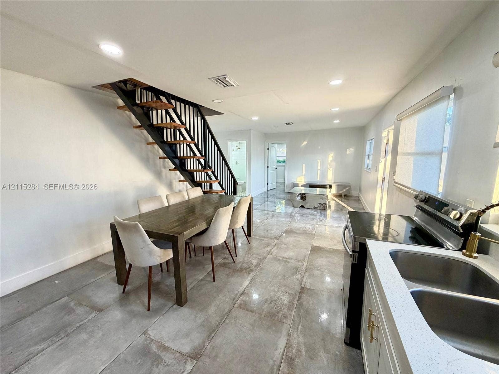 8047 NW 1st Place, Miami, Miami, FL 33150 Open-concept interior featuring large-format tile flooring, recessed ceiling lighting, and a floating staircase with dark metal railings