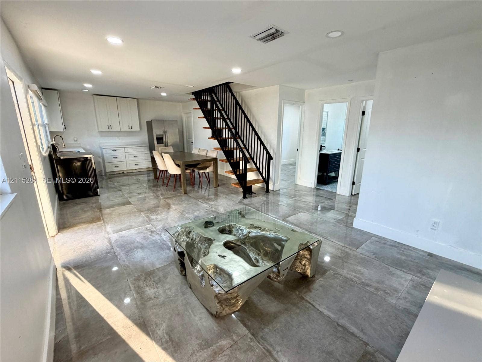 8047 NW 1st Place, Miami, Miami, FL 33150 Open-concept interior featuring large-format tile flooring, a metal staircase with wooden treads, recessed lighting, and cabinetry with integrated stainless steel appliances
