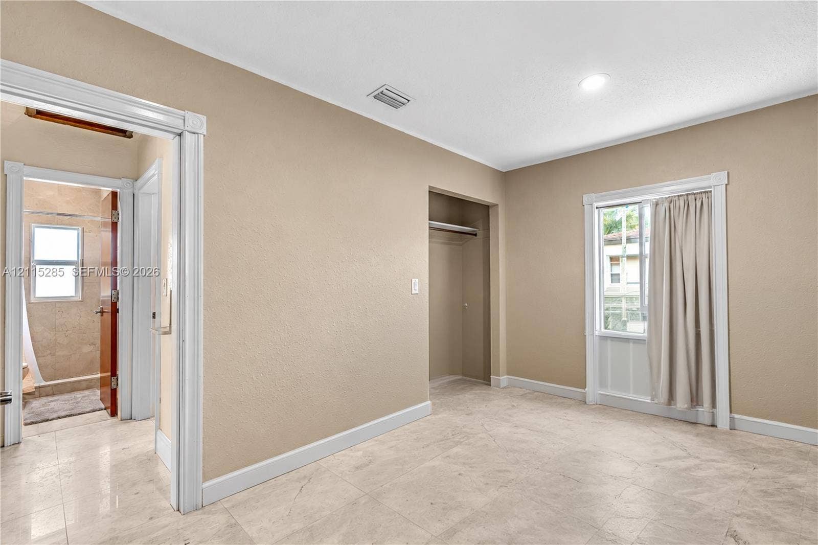 14221 Carver Drive, Miami, FL 33176 Neutral-toned interior featuring large-format tile flooring, a recessed closet with shelving, and crisp white casing around the window and doorway