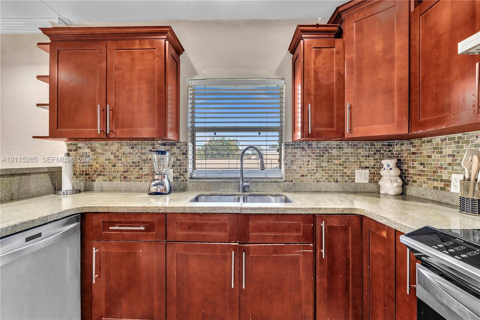 14221 Carver Drive, Miami, FL 33176 Kitchen featuring wood cabinetry, stone-surface countertops, mosaic tile backsplash, dual-basin under-mount sink, and stainless steel hardware