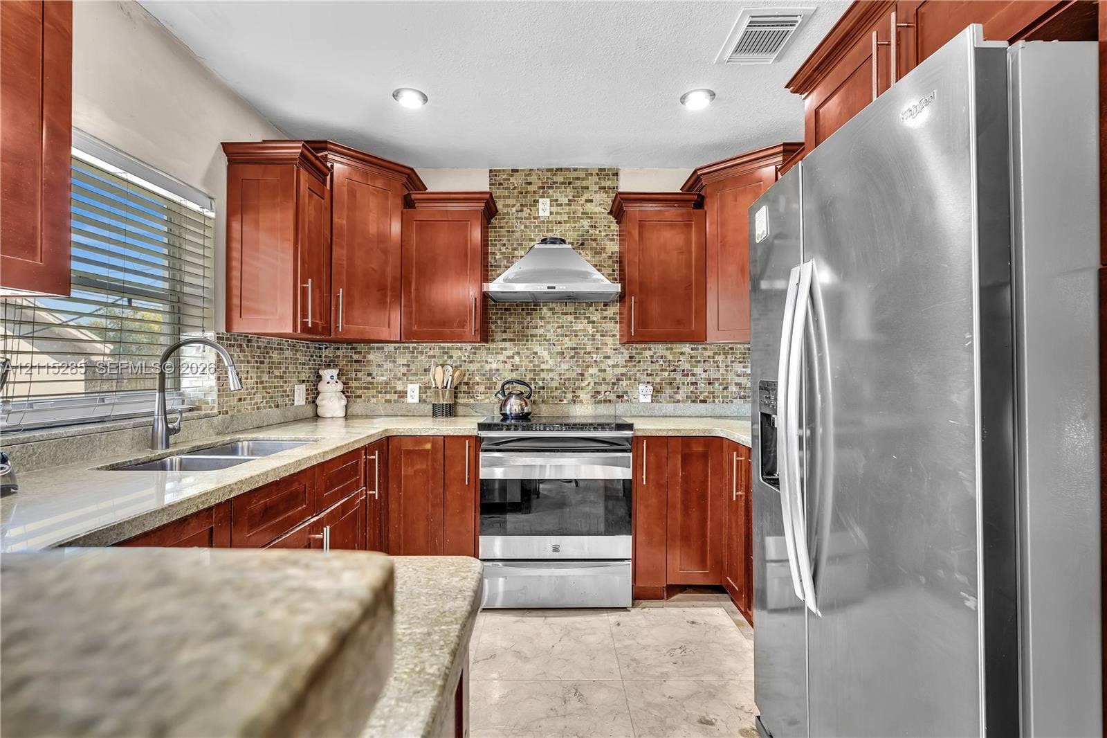 14221 Carver Drive, Miami, FL 33176 Kitchen featuring warm-toned wood cabinetry, mosaic tile backsplash, stainless steel appliances, stone-finish countertops, and recessed lighting