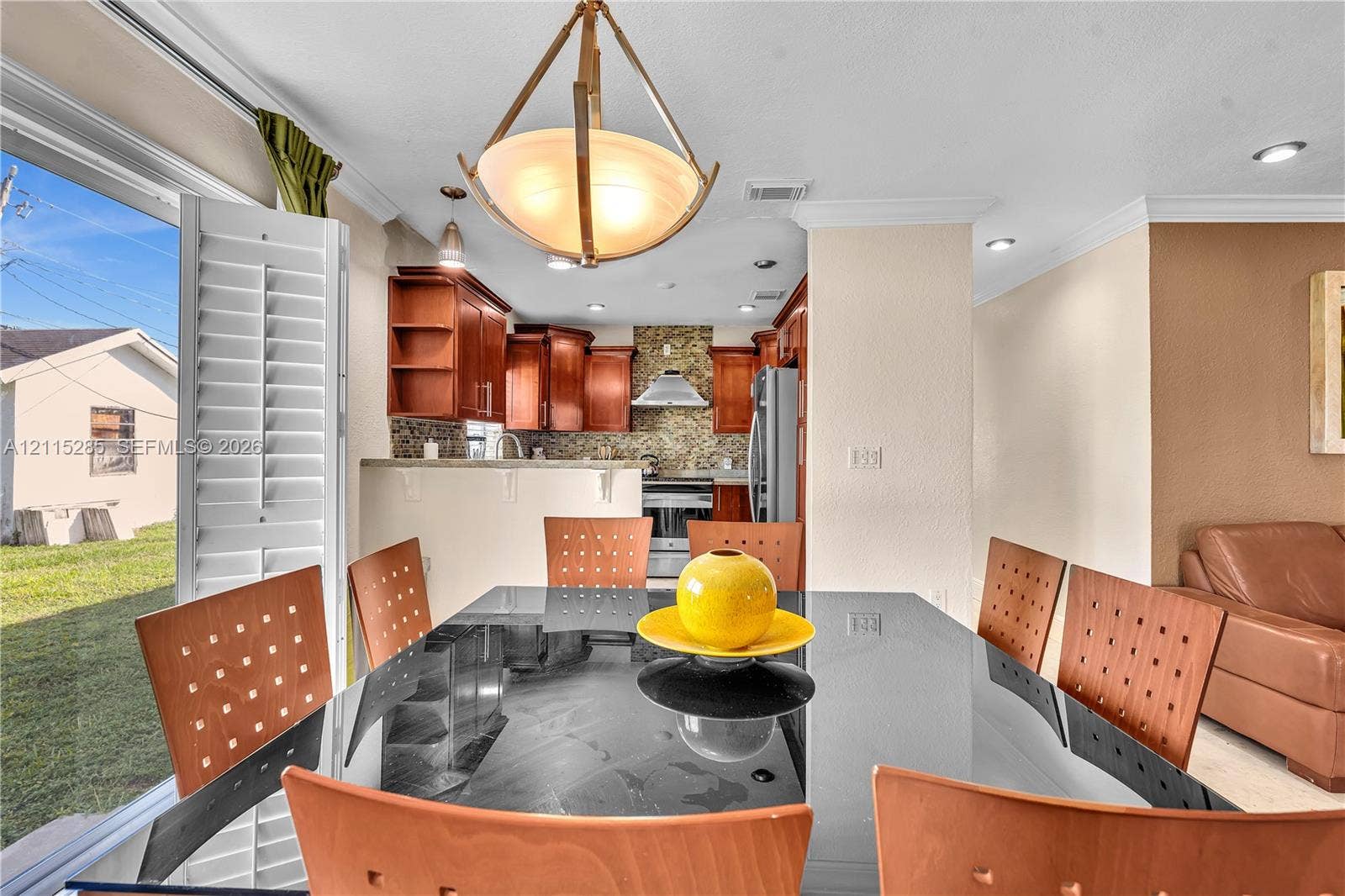 14221 Carver Drive, Miami, FL 33176 Kitchen featuring wood cabinetry, stone-style backsplash, stainless steel appliances, recessed lighting, and a pendant fixture with a frosted glass shade