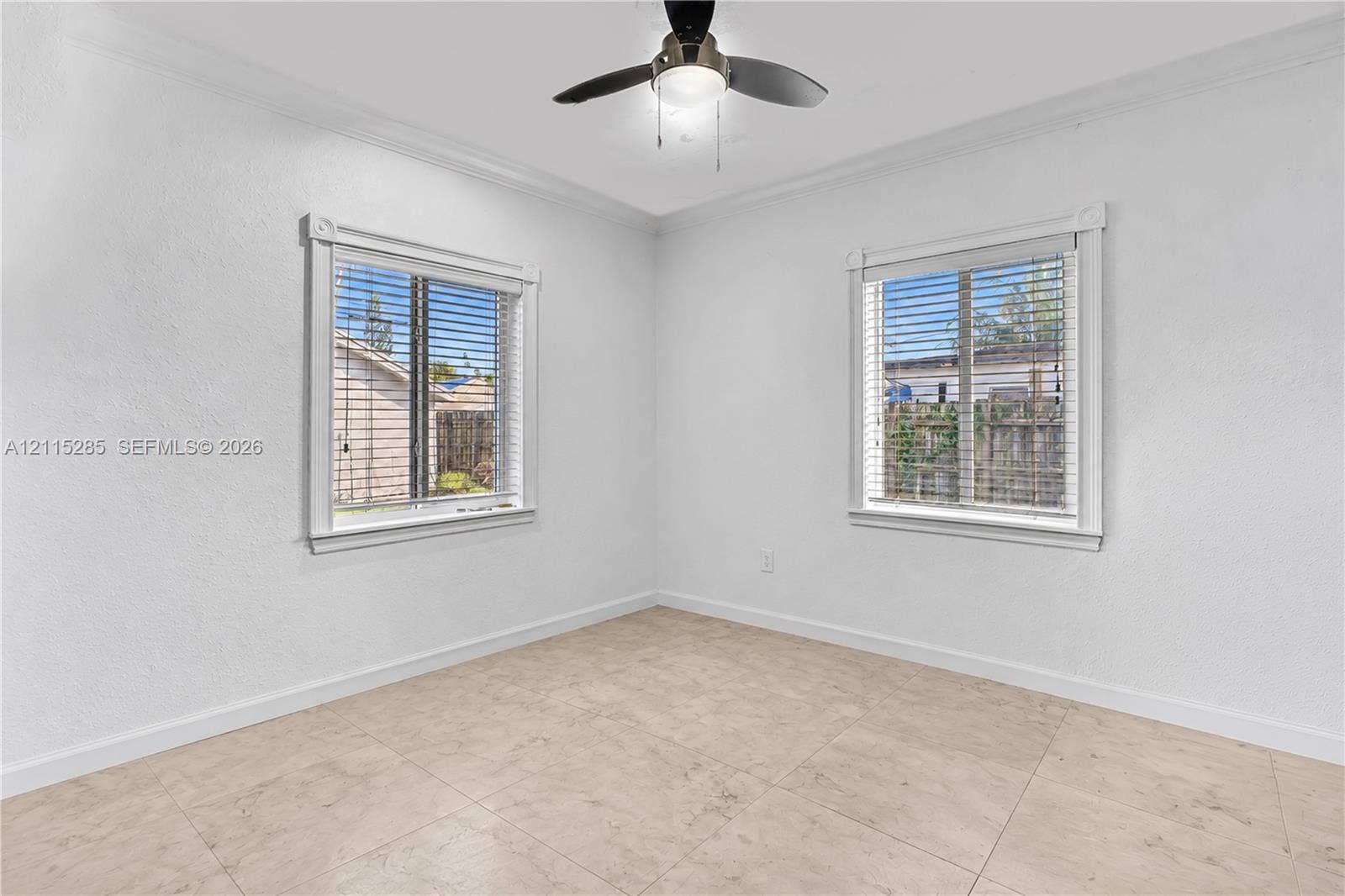 14221 Carver Drive, Miami, FL 33176 Neutral-toned tile flooring, dual windows with decorative millwork trim, and a ceiling-mounted light fixture with a fan