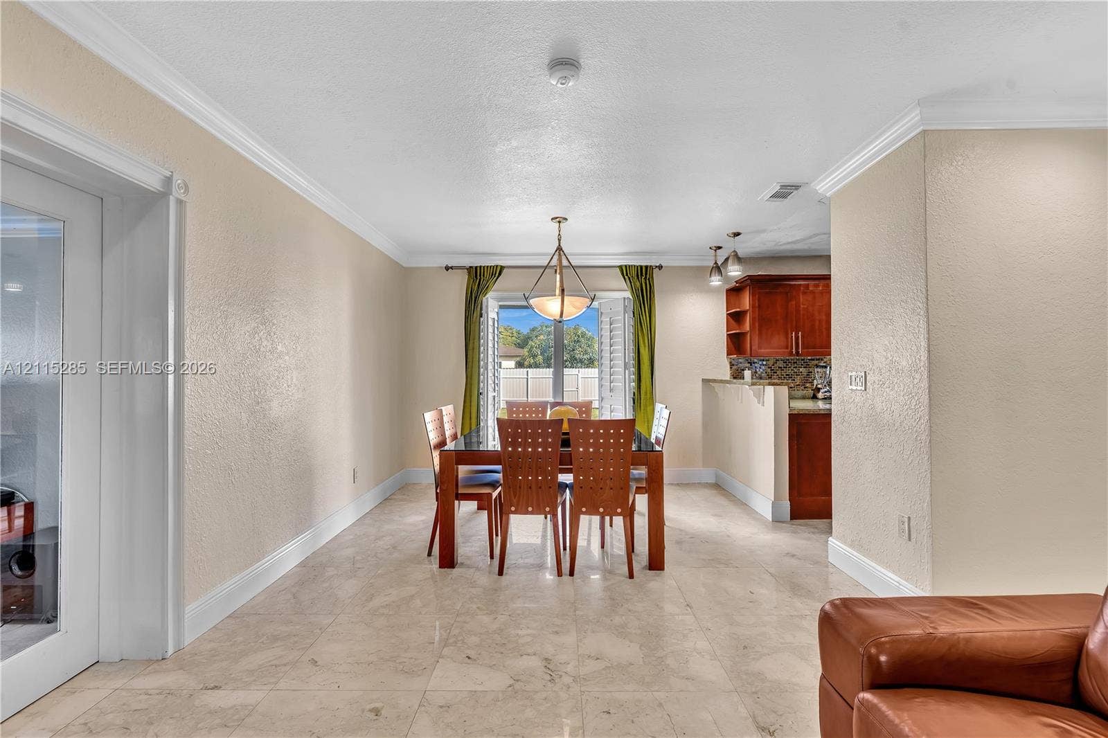 14221 Carver Drive, Miami, FL 33176 Open-concept interior featuring large-format tile flooring, crown molding, a multi-light pendant fixture, and glass-paneled french doors