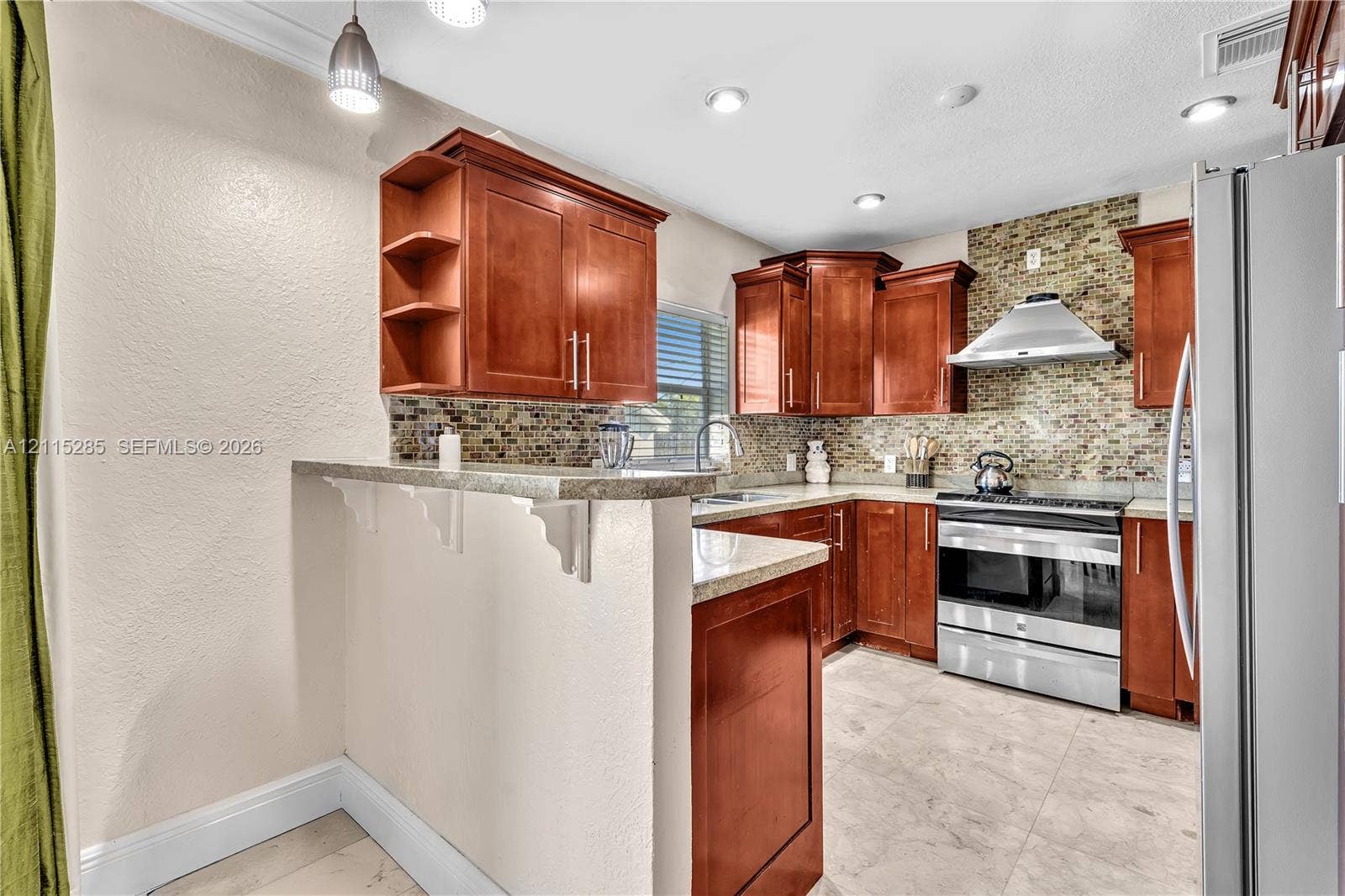 14221 Carver Drive, Miami, FL 33176 Kitchen featuring warm-tone cabinetry, stone-finish countertops, stainless steel appliances, a mosaic tile backsplash, and tile flooring