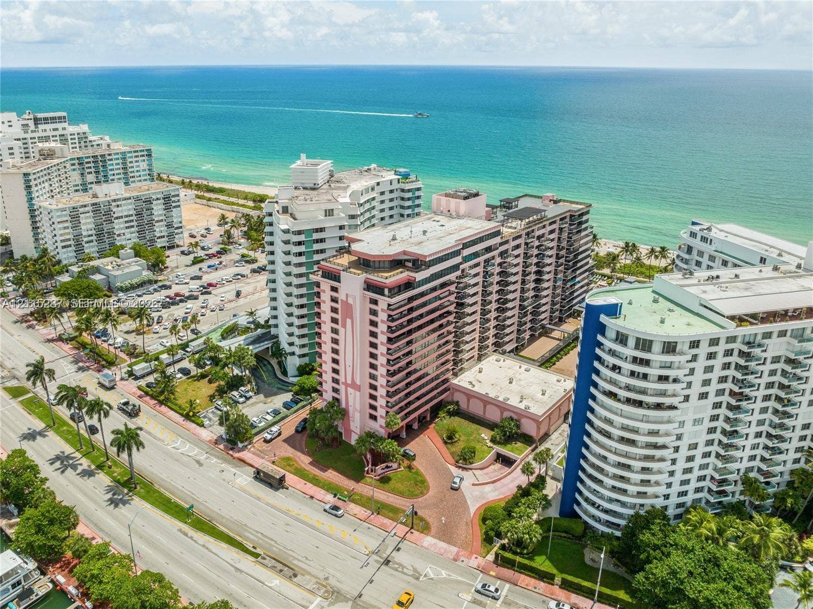 5225 Collins Avenue, #511, Miami Beach, FL 33140 Aerial perspective of coastal high-rise building featuring private balconies, paver-stone driveway, landscaped grounds, and immediate proximity to the oceanfront