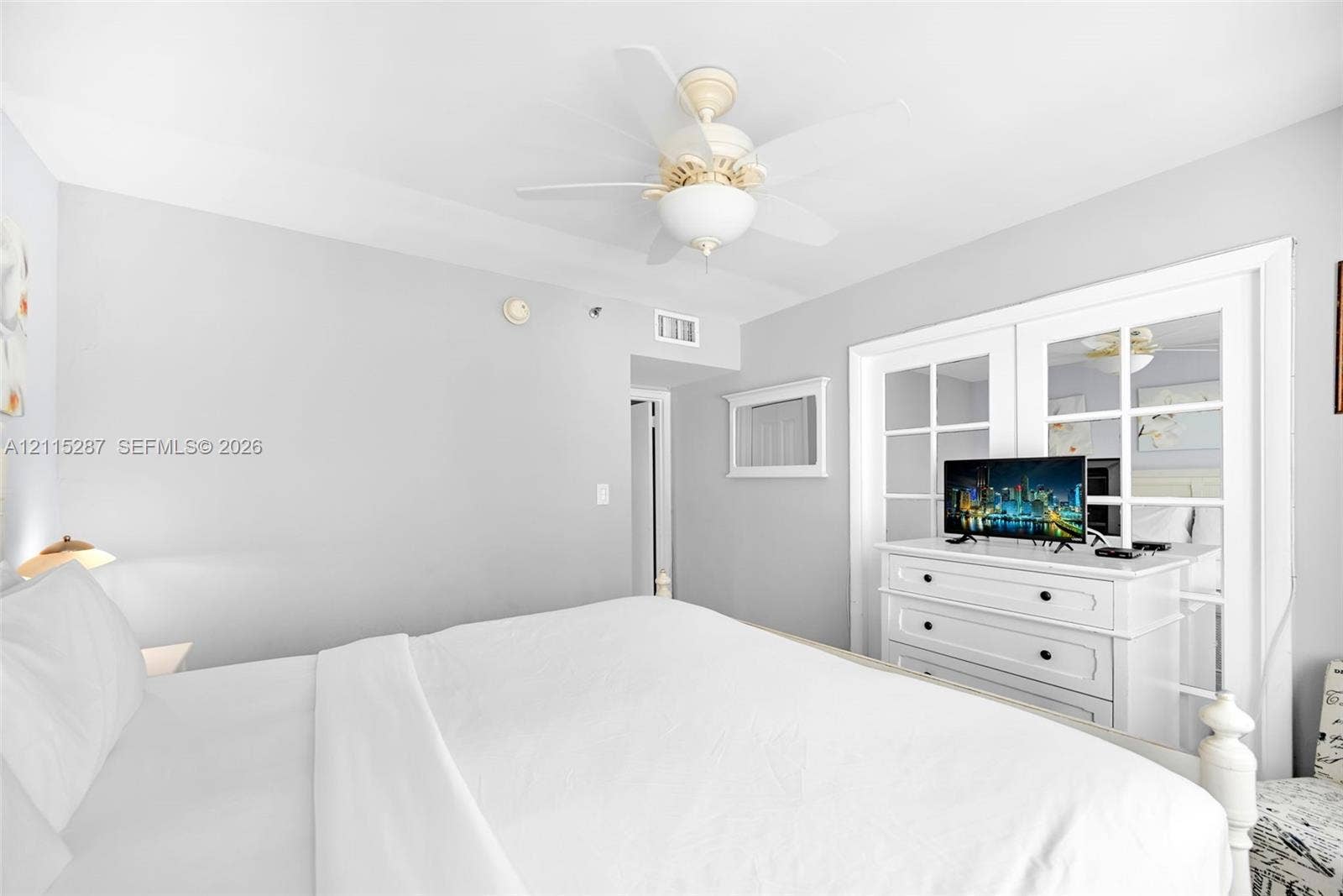 5225 Collins Avenue, #511, Miami Beach, FL 33140 Neutral-toned interior featuring a ceiling fan with integrated lighting and double glass-paneled closet doors