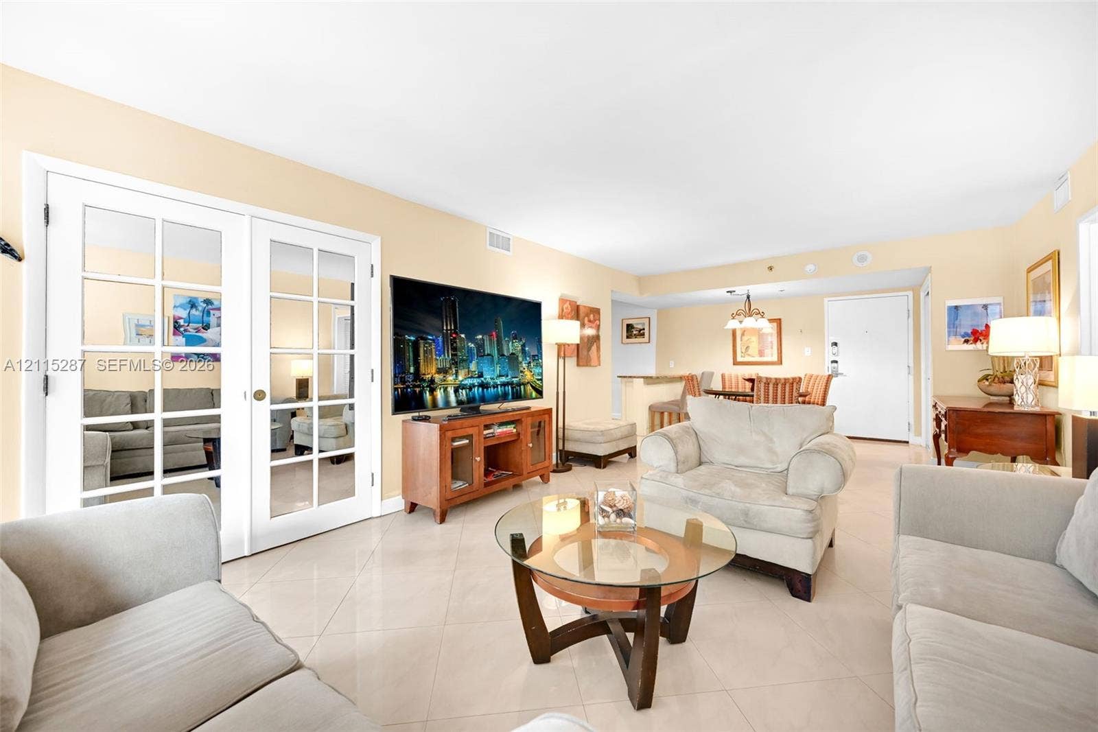 5225 Collins Avenue, #511, Miami Beach, FL 33140 Open-concept interior featuring light-toned tile flooring, French doors with glass panes, and a breakfast bar