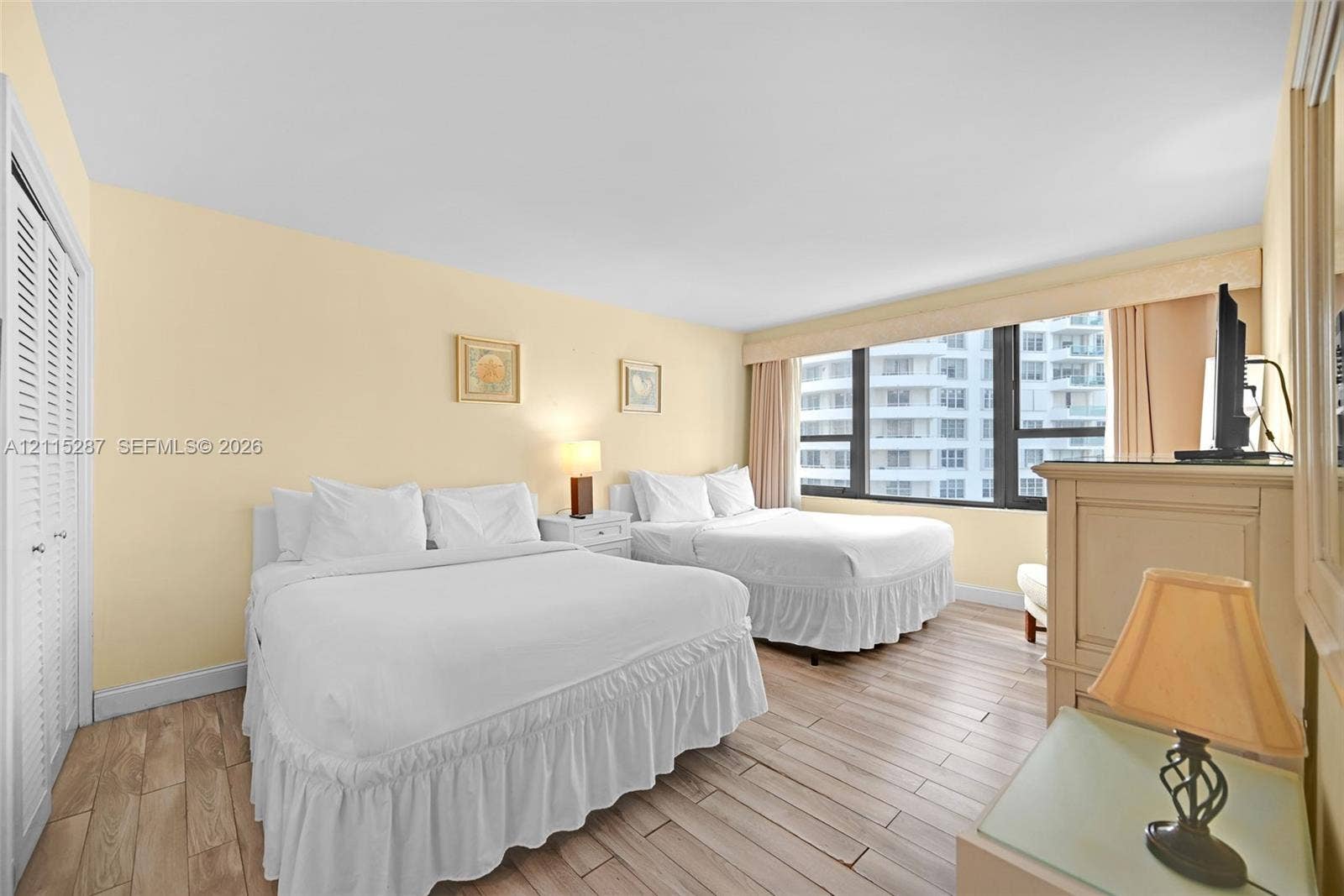 5225 Collins Avenue, #511, Miami Beach, FL 33140 Large floor-to-ceiling windows, wood-finish flooring, and white louvered closet doors