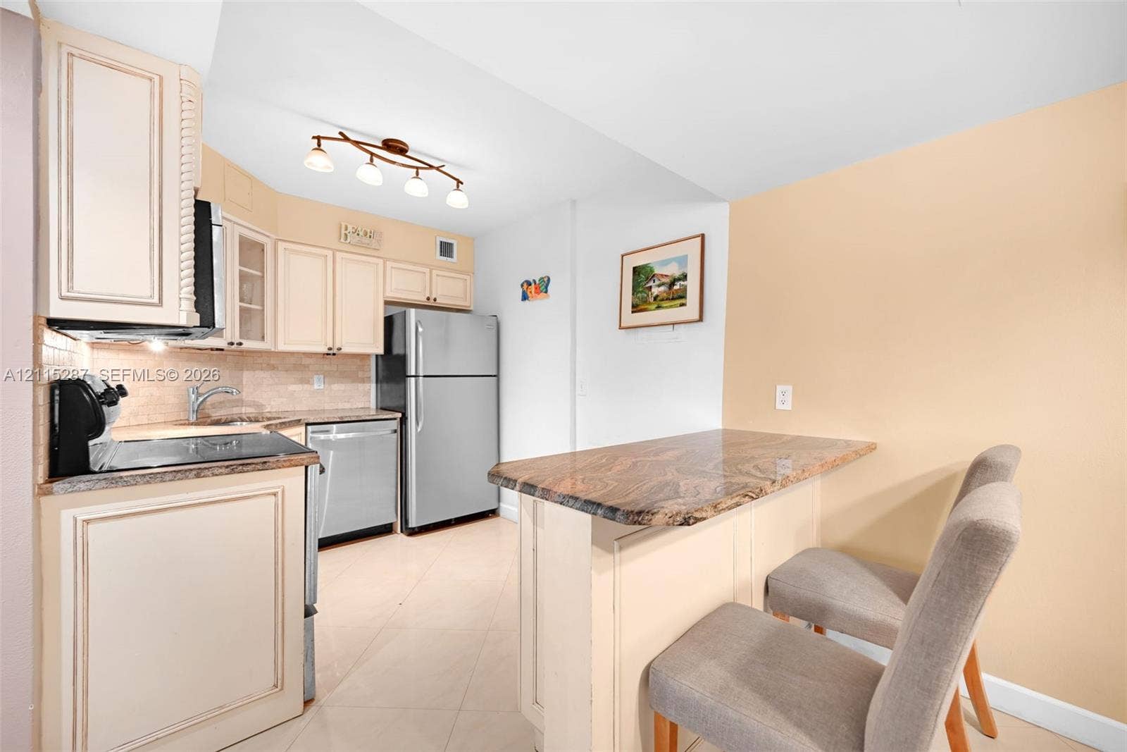 5225 Collins Avenue, #511, Miami Beach, FL 33140 Kitchen featuring custom cabinetry, stone-surfaced countertops, a stone-tiled backsplash, stainless steel appliances, and a breakfast bar
