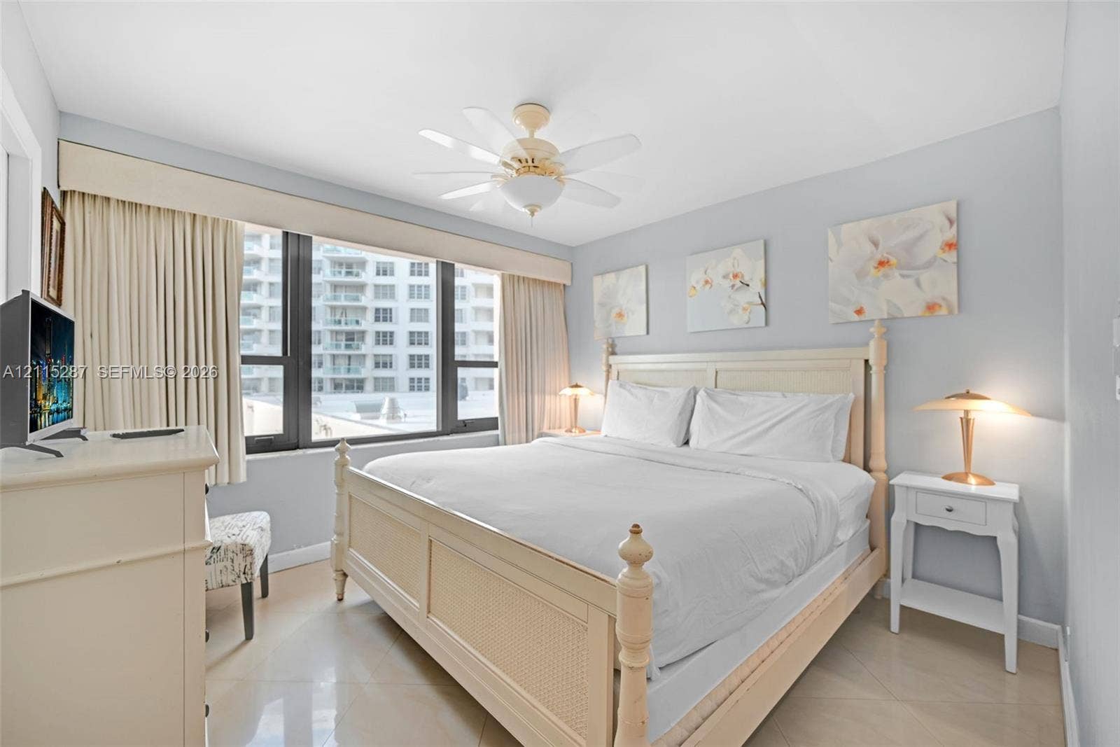 5225 Collins Avenue, #511, Miami Beach, FL 33140 Large floor-to-ceiling windows with custom cornice detailing, light-toned tiled flooring, and a ceiling-mounted fan fixture