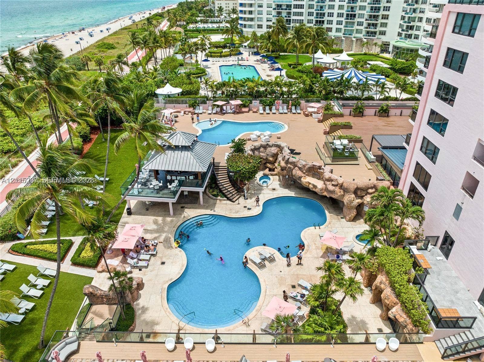 5225 Collins Avenue, #511, Miami Beach, FL 33140 Multi-level swimming pools with rock features, poolside pavilion, integrated hot tub, landscaped grounds, and paved patio surfaces