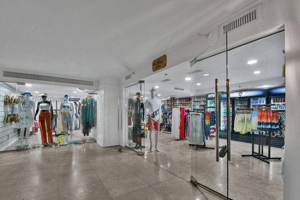 5225 Collins Avenue, #511, Miami Beach, FL 33140 Commercial interior featuring polished stone tile flooring, recessed ceiling lighting, and frameless glass entry doors with metallic hardware