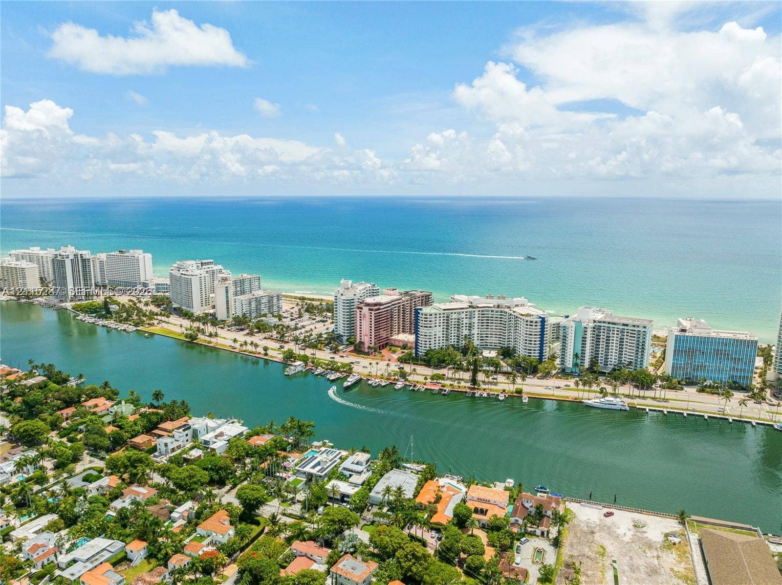5225 Collins Avenue, #511, Miami Beach, FL 33140 Aerial perspective of a coastal residential area featuring a deep-water canal, proximity to the Atlantic Ocean, mature tropical landscaping, and regional shoreline access