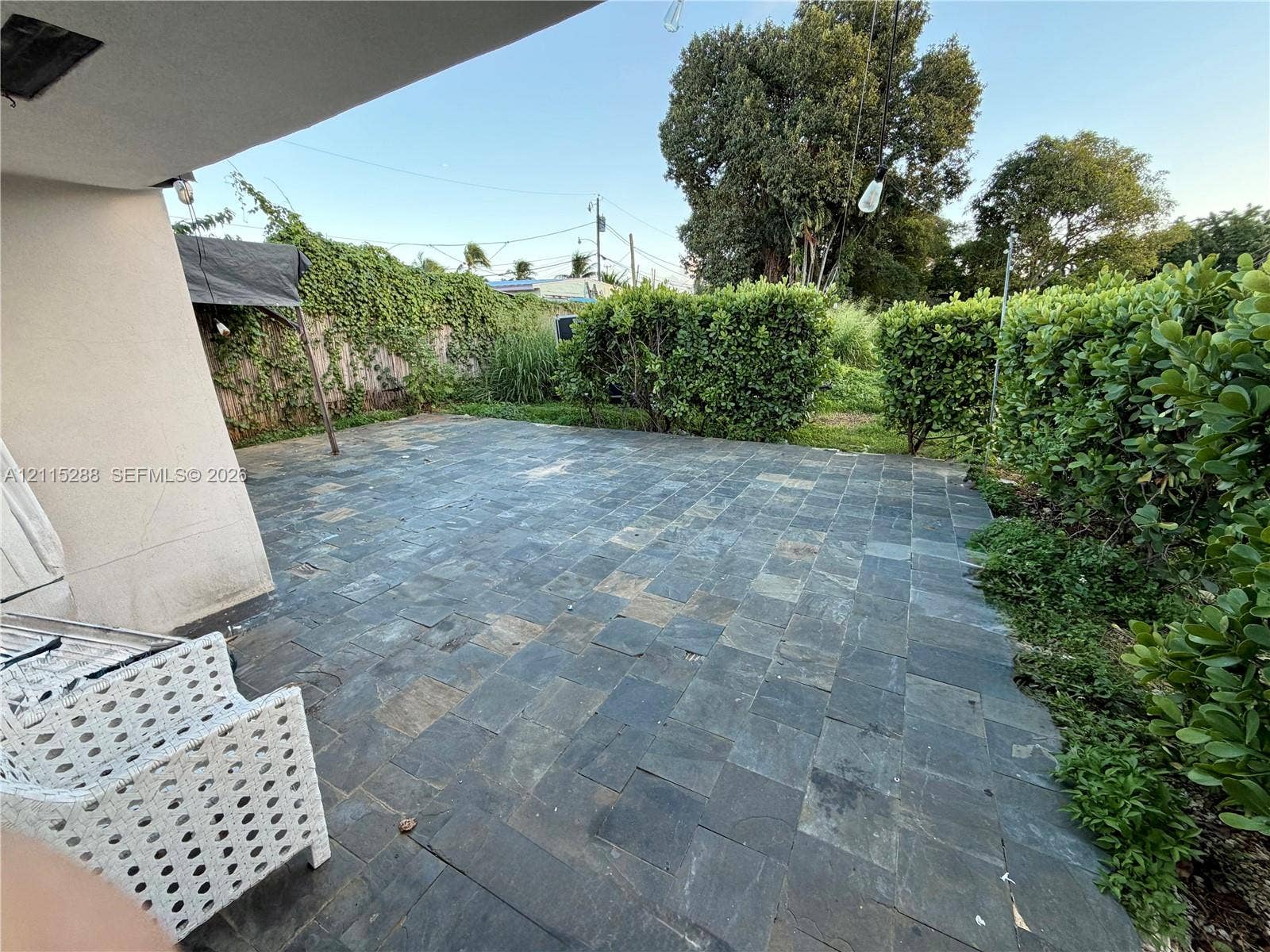 8017 NW 1st Place, Miami, Miami, FL 33150 Outdoor patio featuring natural stone tile flooring, covered overhang, and perimeter shrubbery