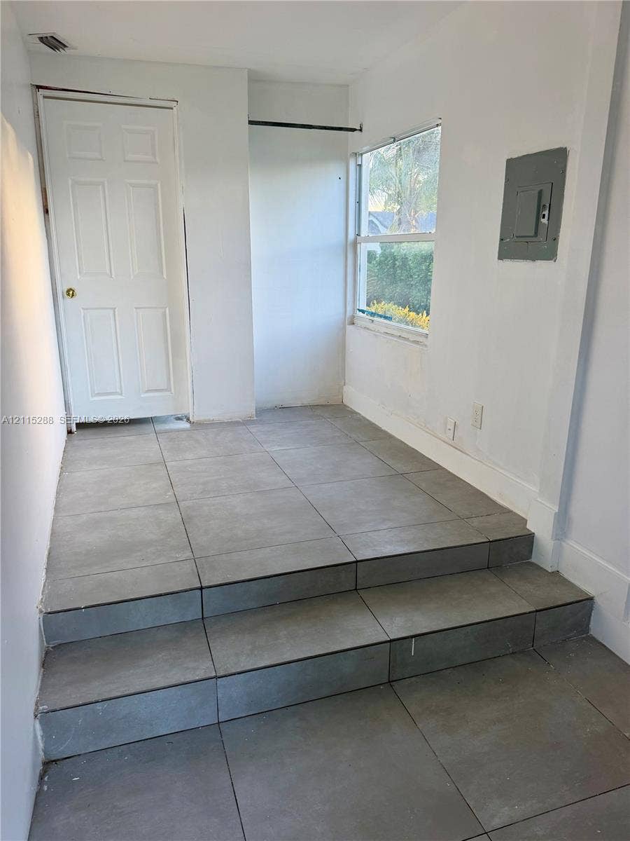 8017 NW 1st Place, Miami, Miami, FL 33150 Interior space featuring large-format grey tile flooring, a multi-level stepped transition, a single-panel interior door, and a horizontal window