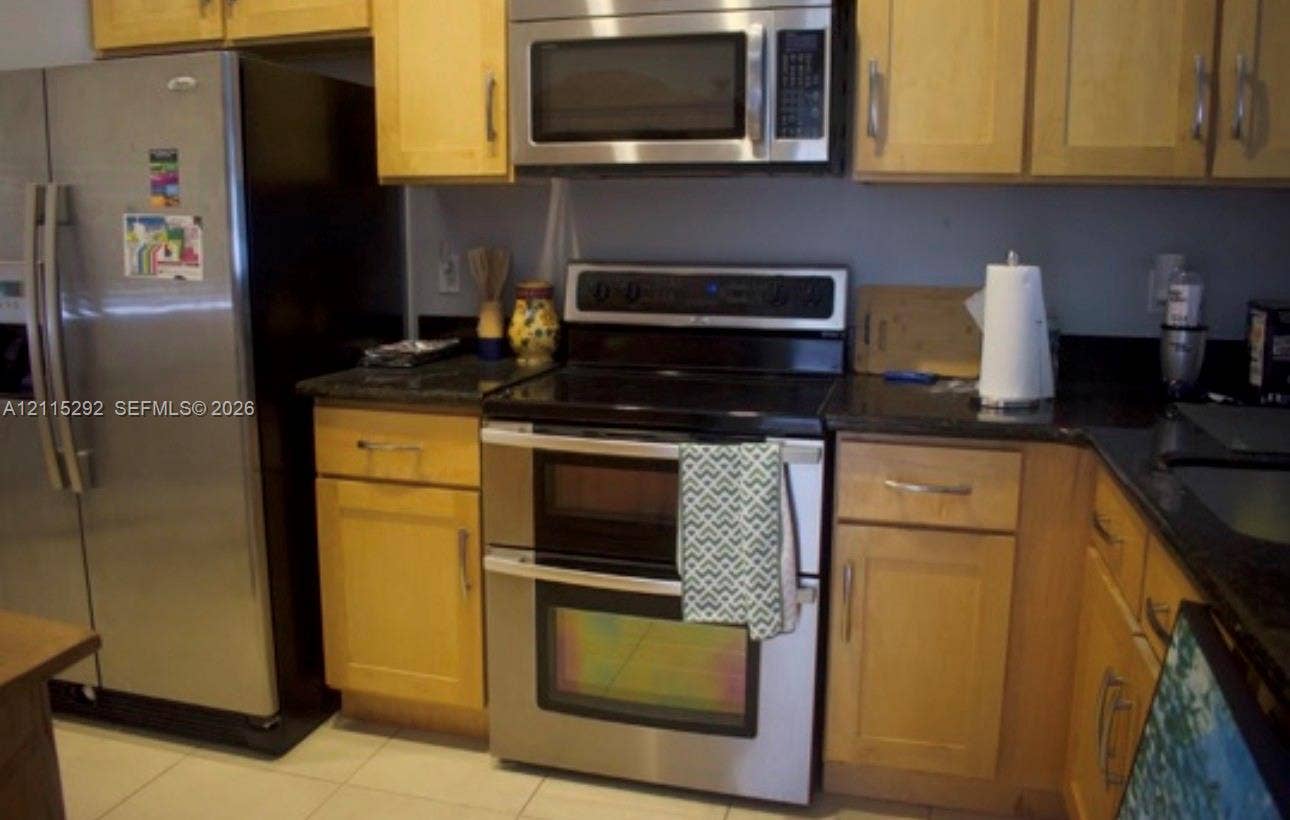 2700 SW 55th Street, #1, Dania, Dania Beach, FL 33312 Kitchen featuring light-finish wood cabinetry, dark stone countertops, stainless steel side-by-side refrigerator, stainless steel double oven, and stainless steel over-the-range microwave
