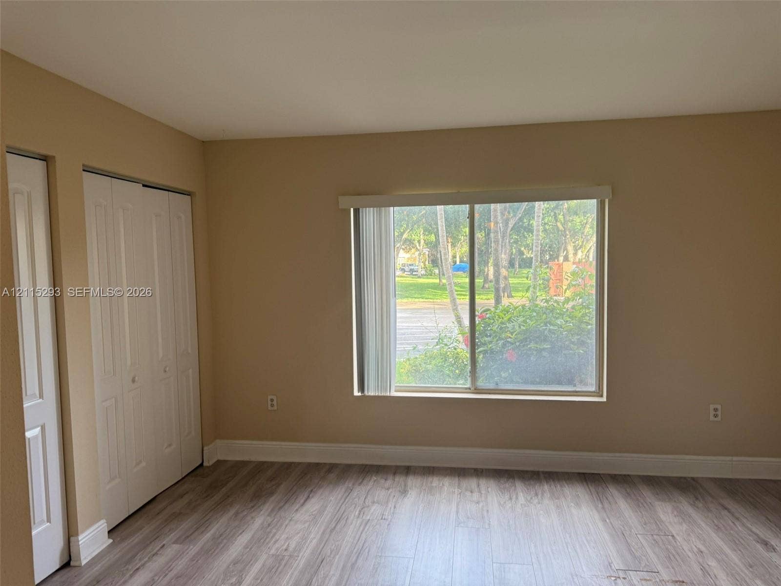 2642 NW 33rd Street, #1902, Oakland Park, Oakland Park, FL 33309 Interior room featuring wood-finish flooring, a large sliding window, and two sets of bi-fold closet doors