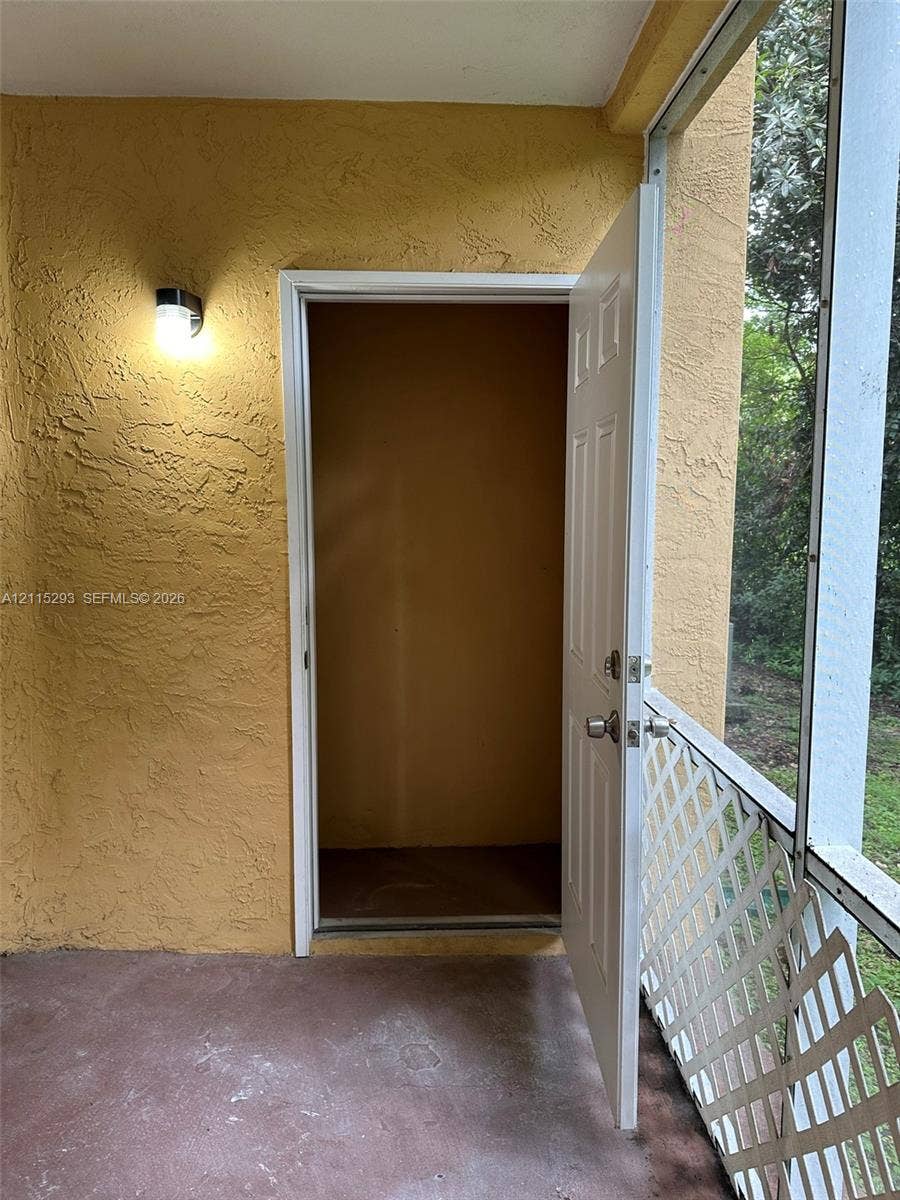 2642 NW 33rd Street, #1902, Oakland Park, Oakland Park, FL 33309 Enclosed porch featuring textured stucco walls, exterior wall-mounted lighting, and a storage closet with a six-panel door, bordered by white lattice screening