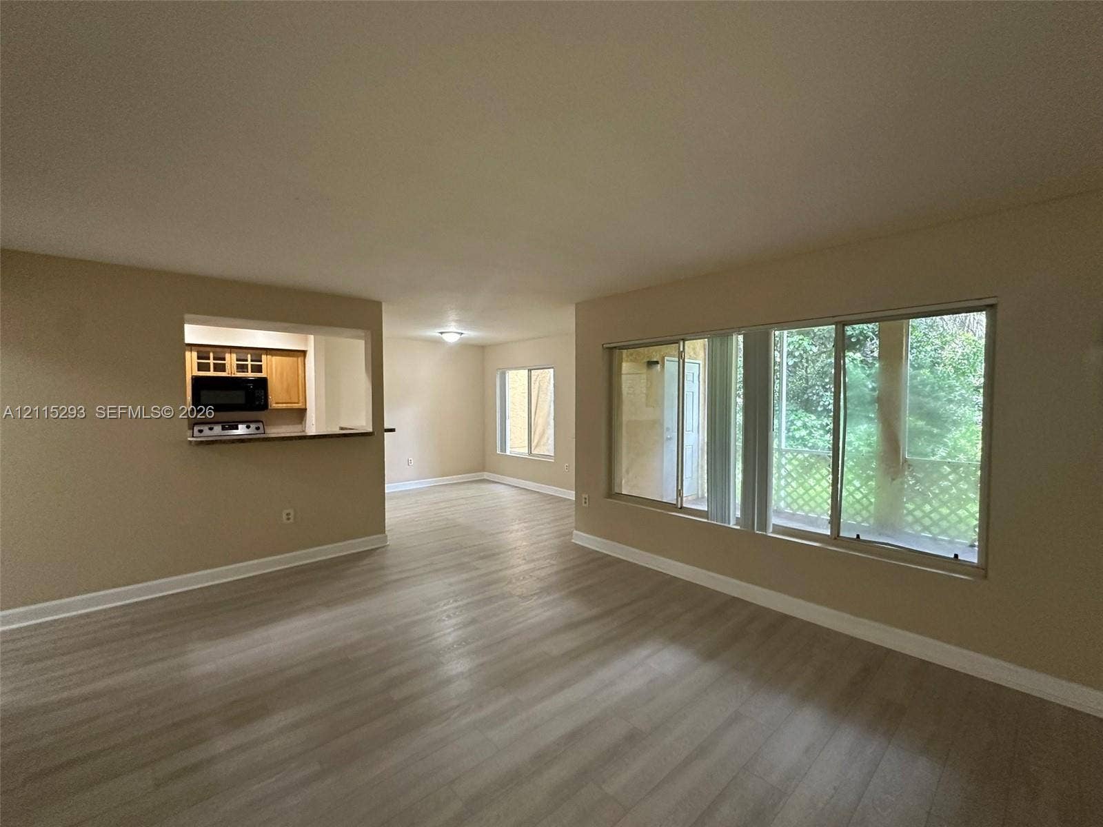 2642 NW 33rd Street, #1902, Oakland Park, Oakland Park, FL 33309 Interior featuring wood-finish flooring, a large picture window, and a pass-through opening to the kitchen area