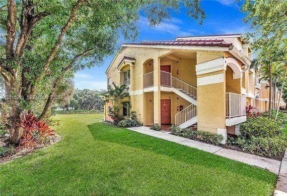 2642 NW 33rd Street, #1902, Oakland Park, Oakland Park, FL 33309 Multi-story exterior featuring stucco siding, a tiled roof, open-air staircases with metal railings, and a concrete walkway