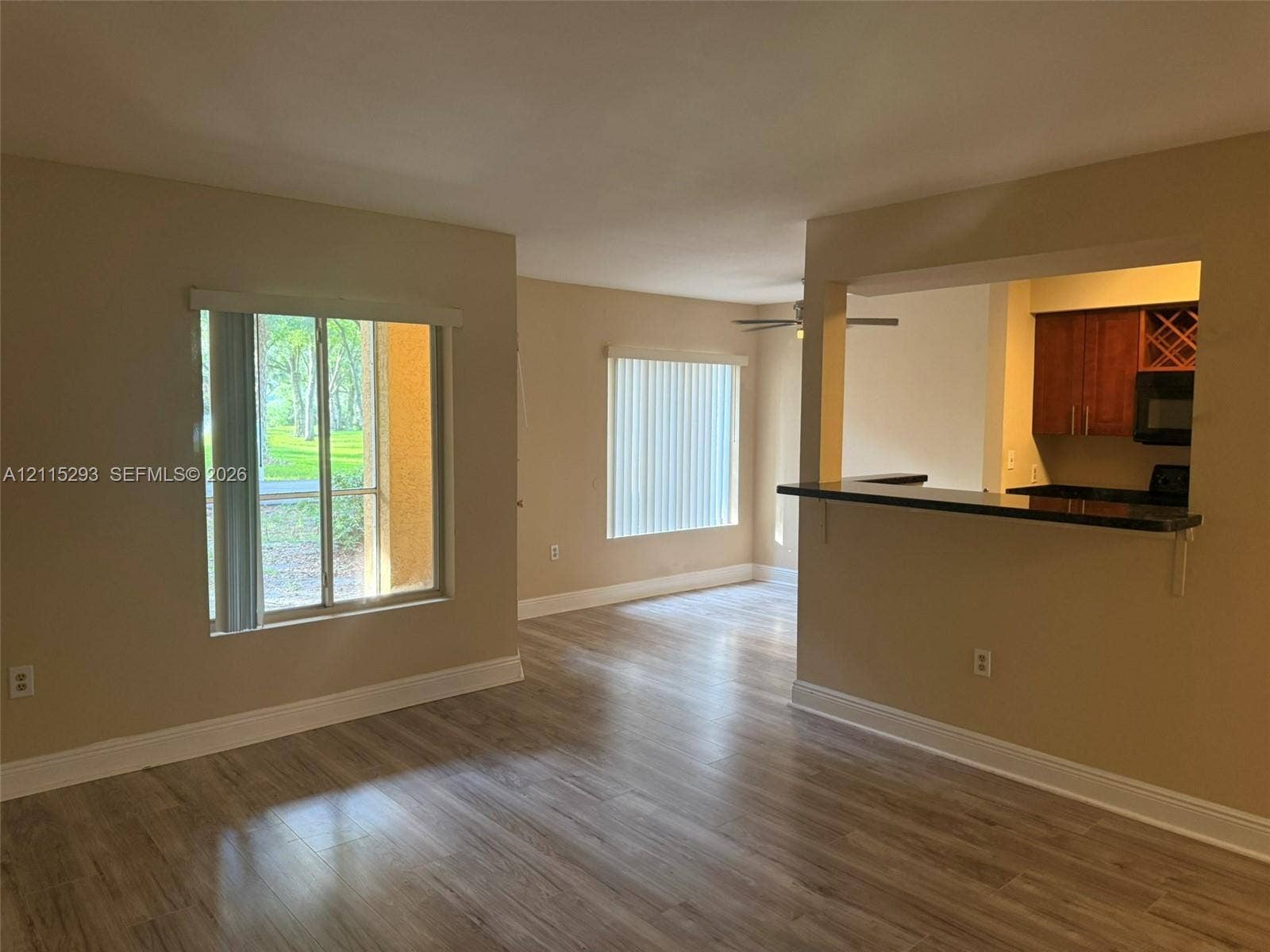 2642 NW 33rd Street, #1902, Oakland Park, Oakland Park, FL 33309 Living area featuring wood-finish flooring, a pass-through opening, dark-toned kitchen cabinetry, a breakfast bar, and multiple windows