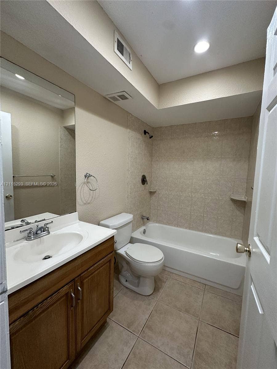 2642 NW 33rd Street, #1902, Oakland Park, Oakland Park, FL 33309 Bathroom featuring a wood-finish vanity with a white countertop, large wall-mounted mirror, ceramic tile flooring, and a tiled tub-shower combination