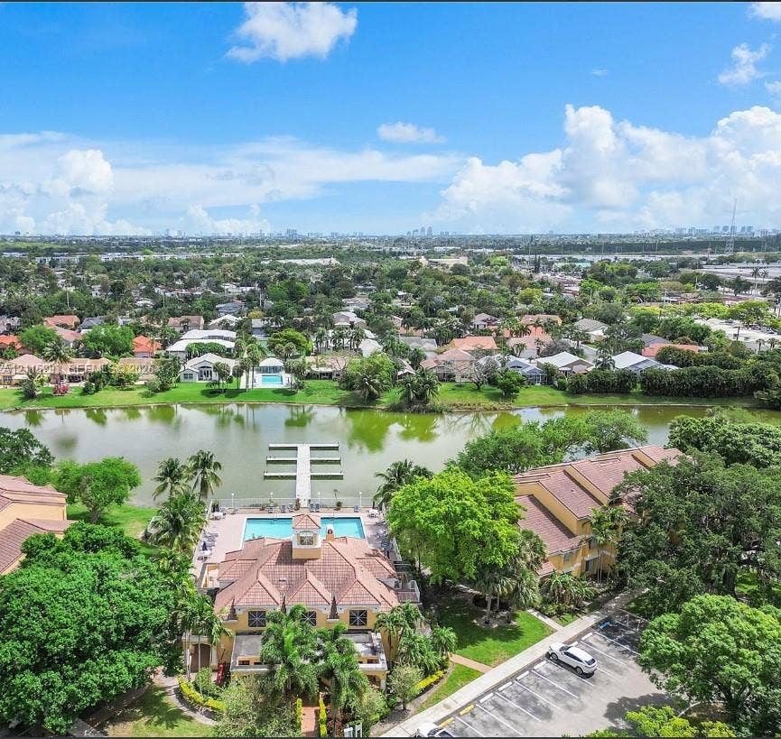 2642 NW 33rd Street, #1902, Oakland Park, Oakland Park, FL 33309 Aerial perspective of property grounds featuring a swimming pool, a private dock extending into the lake, a multi-story structure with a tiled roof, and mature landscaping