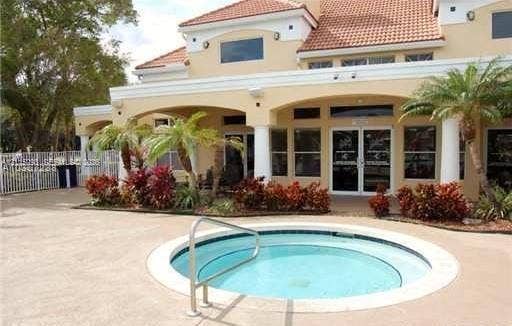 2642 NW 33rd Street, #1902, Oakland Park, Oakland Park, FL 33309 In-ground spa with a metal handrail, concrete deck, covered patio, stucco exterior, and multi-pitched tile roof
