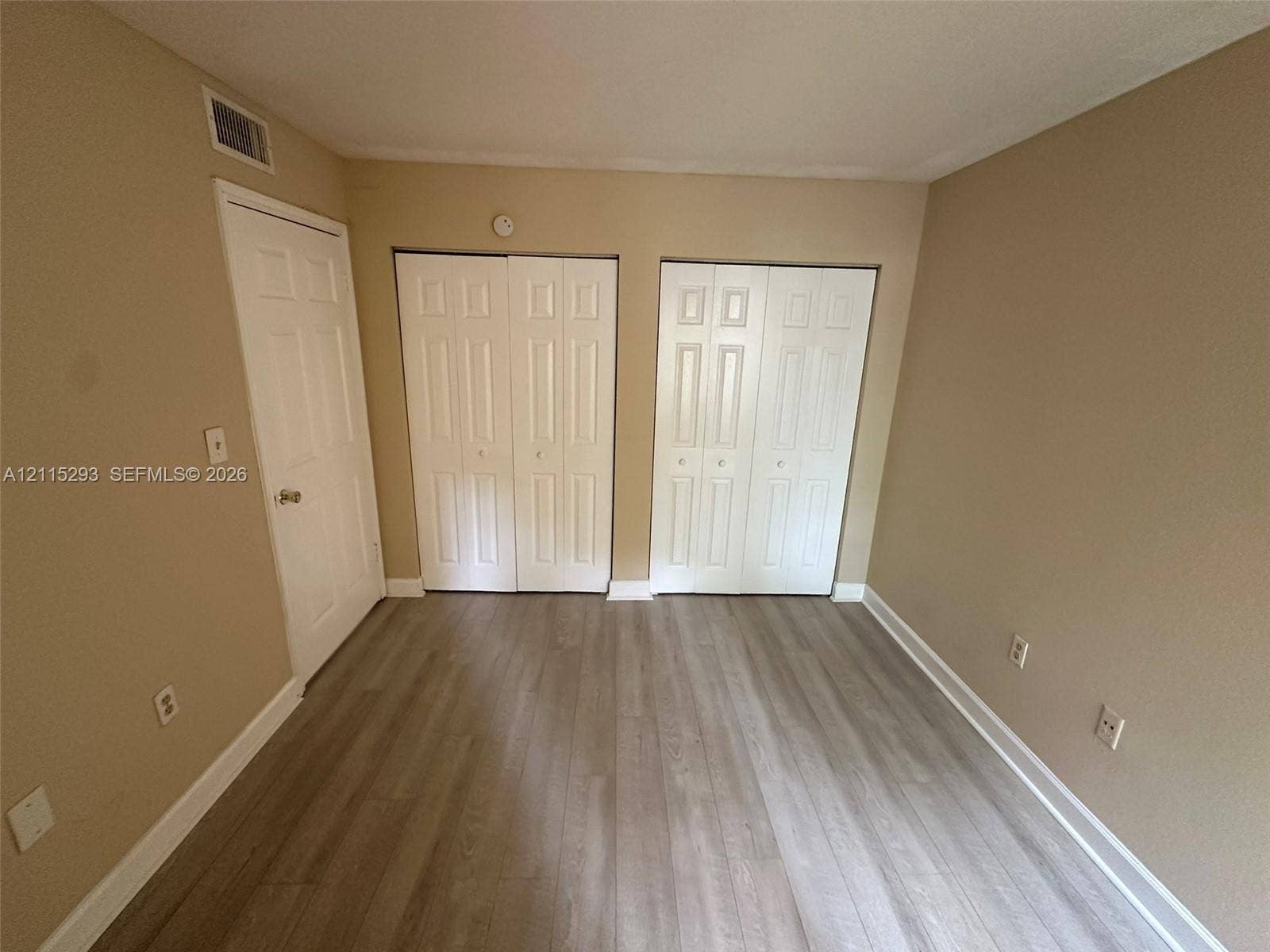2642 NW 33rd Street, #1902, Oakland Park, Oakland Park, FL 33309 Room featuring neutral wall paint, wood-finish flooring, and dual bi-fold closet doors