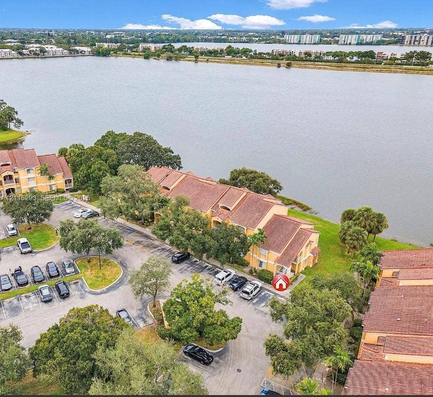 2642 NW 33rd Street, #1902, Oakland Park, Oakland Park, FL 33309 Aerial perspective of a multi-story building featuring terracotta-toned roof tiles, stucco exterior walls, paved surface parking, and waterfront positioning
