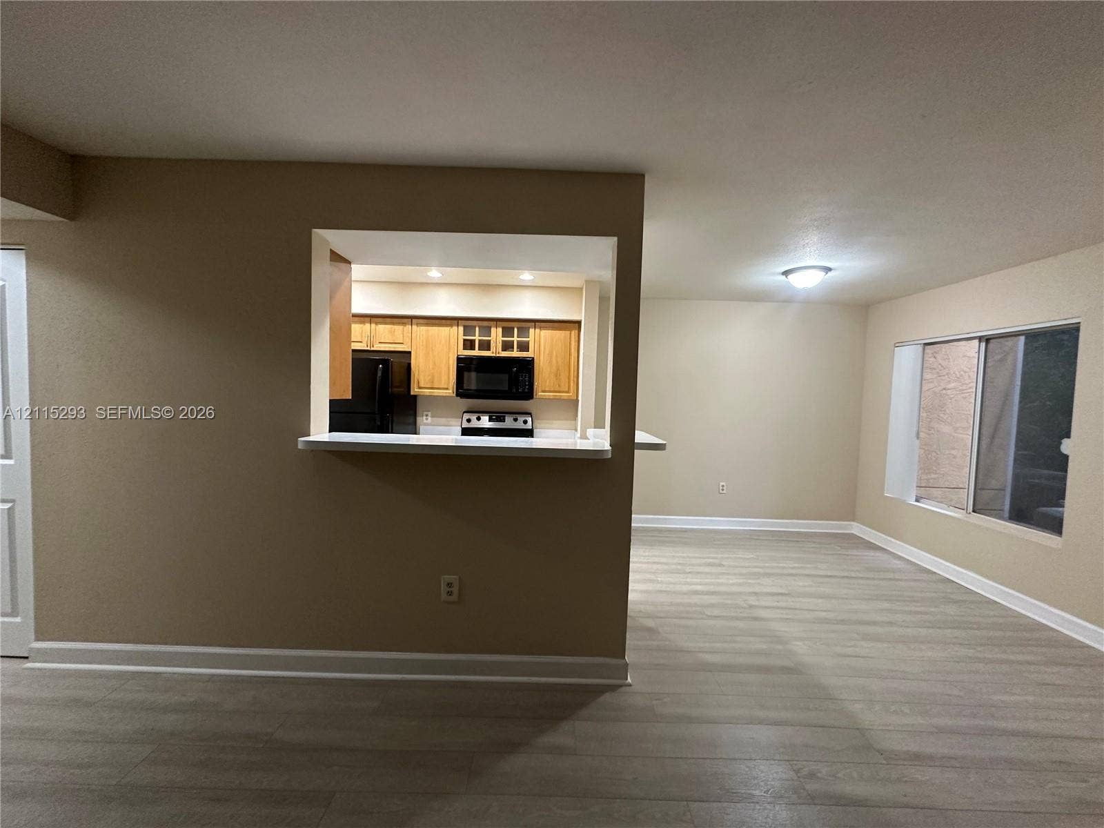 2642 NW 33rd Street, #1902, Oakland Park, Oakland Park, FL 33309 Interior space featuring wood-finish flooring, a pass-through kitchen window with a breakfast bar, recessed ceiling lighting, and a large sliding glass door