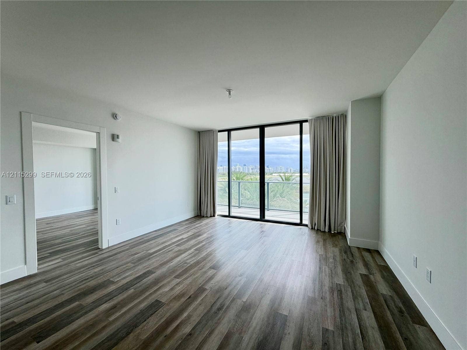 Open-concept room featuring wood-finish flooring, floor-to-ceiling glass sliding doors, and a private balcony