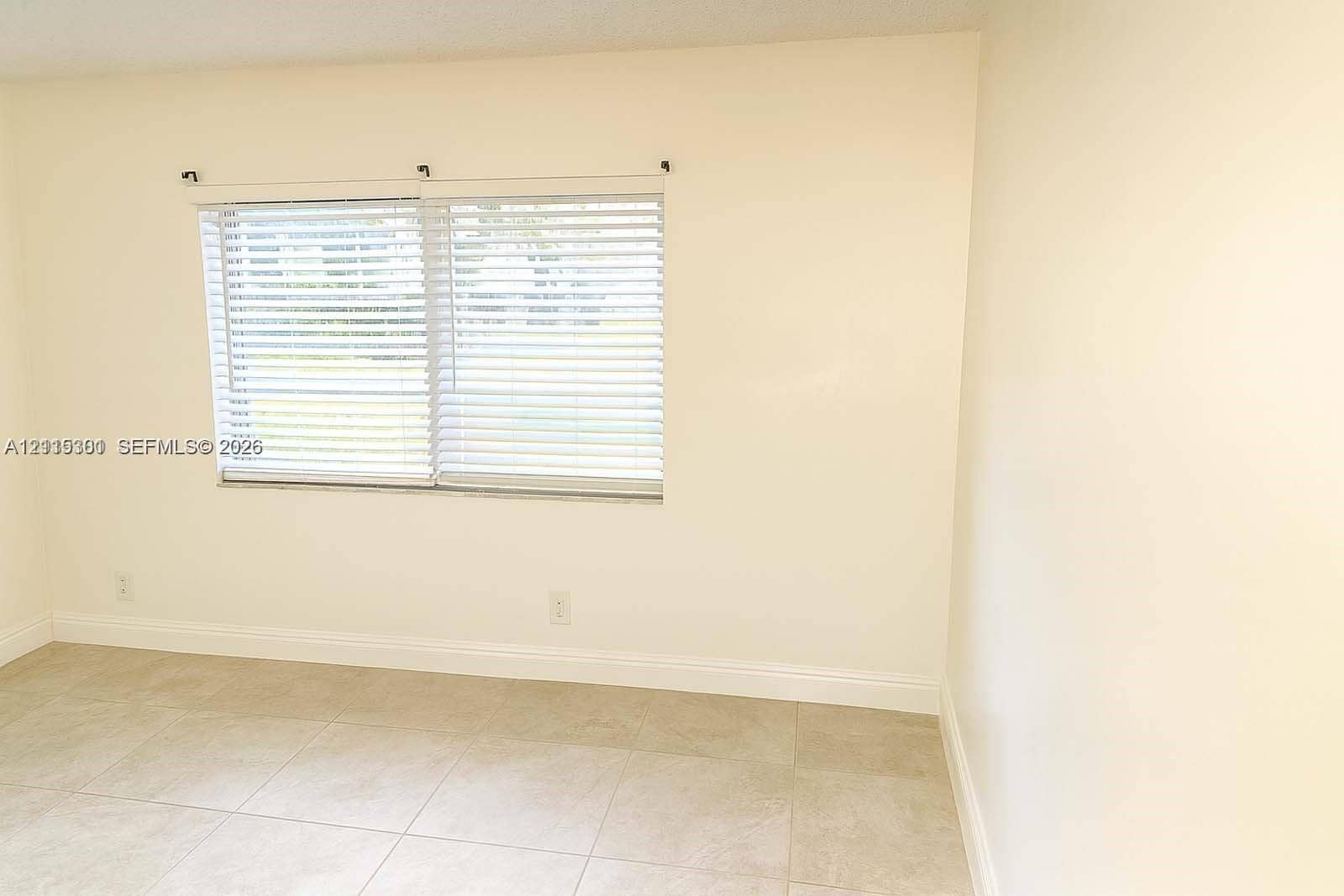 1630 Embassy Drive, #101, West Palm Beach, West Palm Beach, FL 33401 Neutral-toned interior space featuring light-colored tile flooring, smooth walls, and horizontal slat window blinds