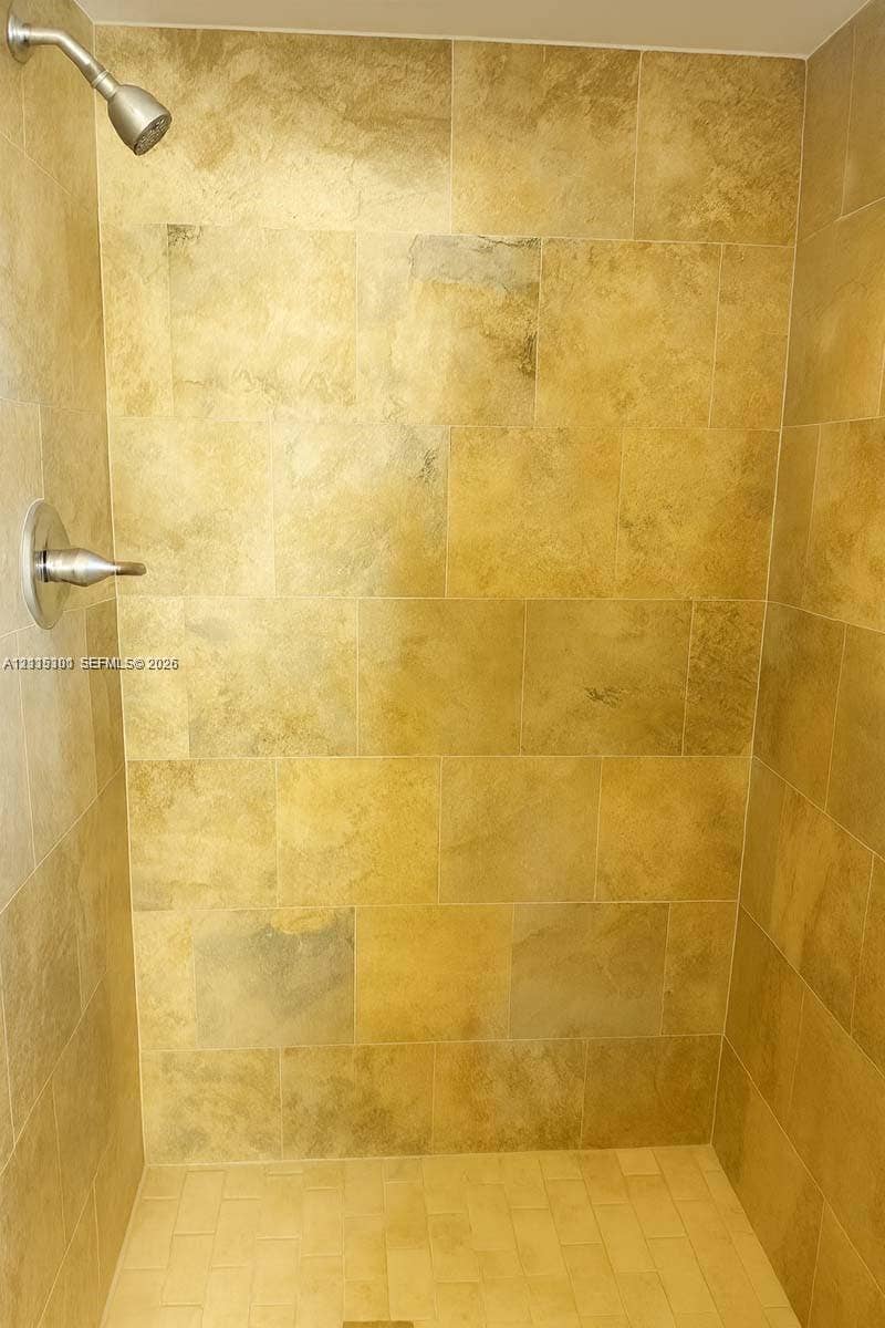 1630 Embassy Drive, #101, West Palm Beach, West Palm Beach, FL 33401 Walk-in shower featuring large-format textured stone wall tile, linear tile floor, and polished metal shower fixtures