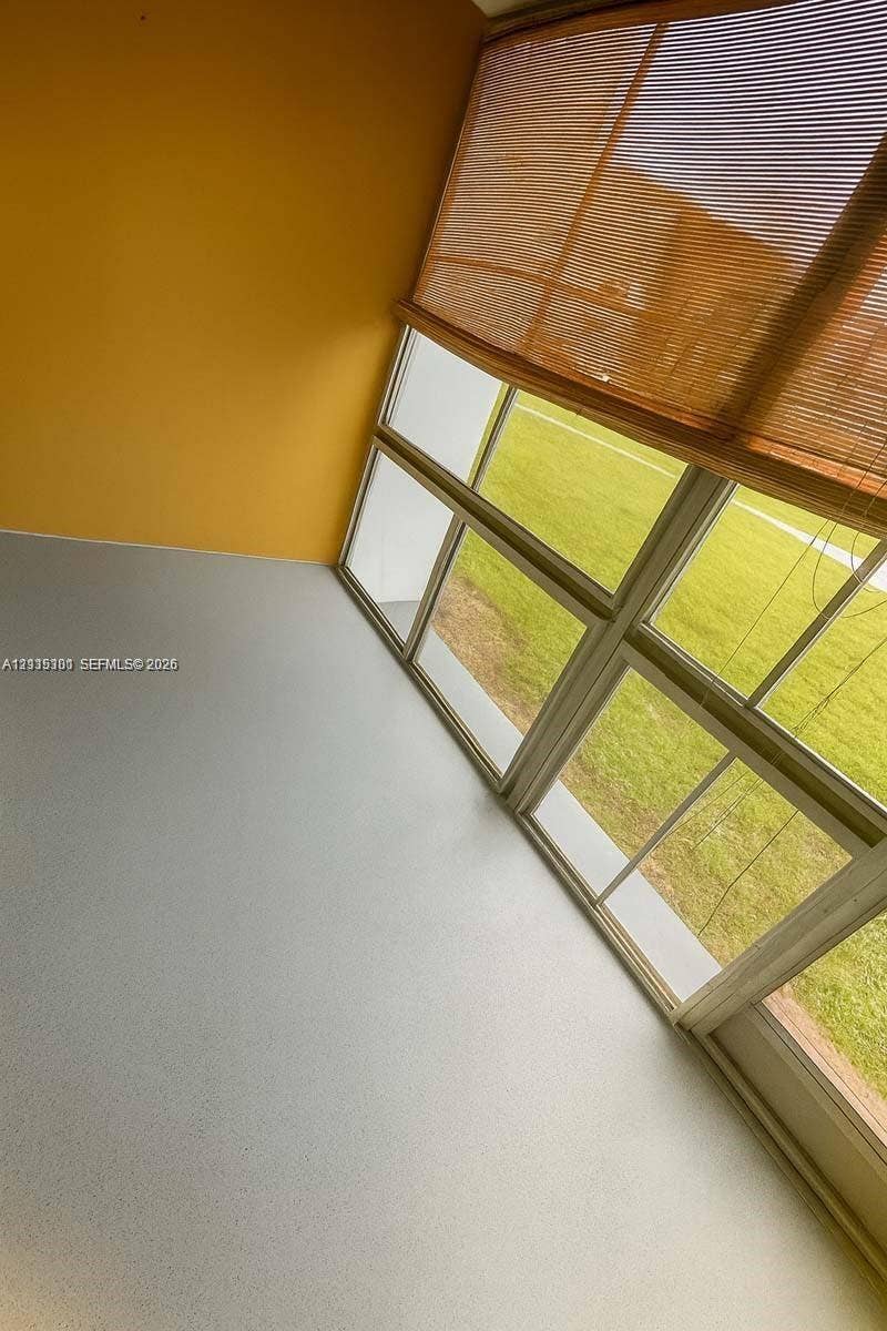 1630 Embassy Drive, #101, West Palm Beach, West Palm Beach, FL 33401 Enclosed balcony featuring multi-pane glass windows, neutral flooring, and yellow wall finishes